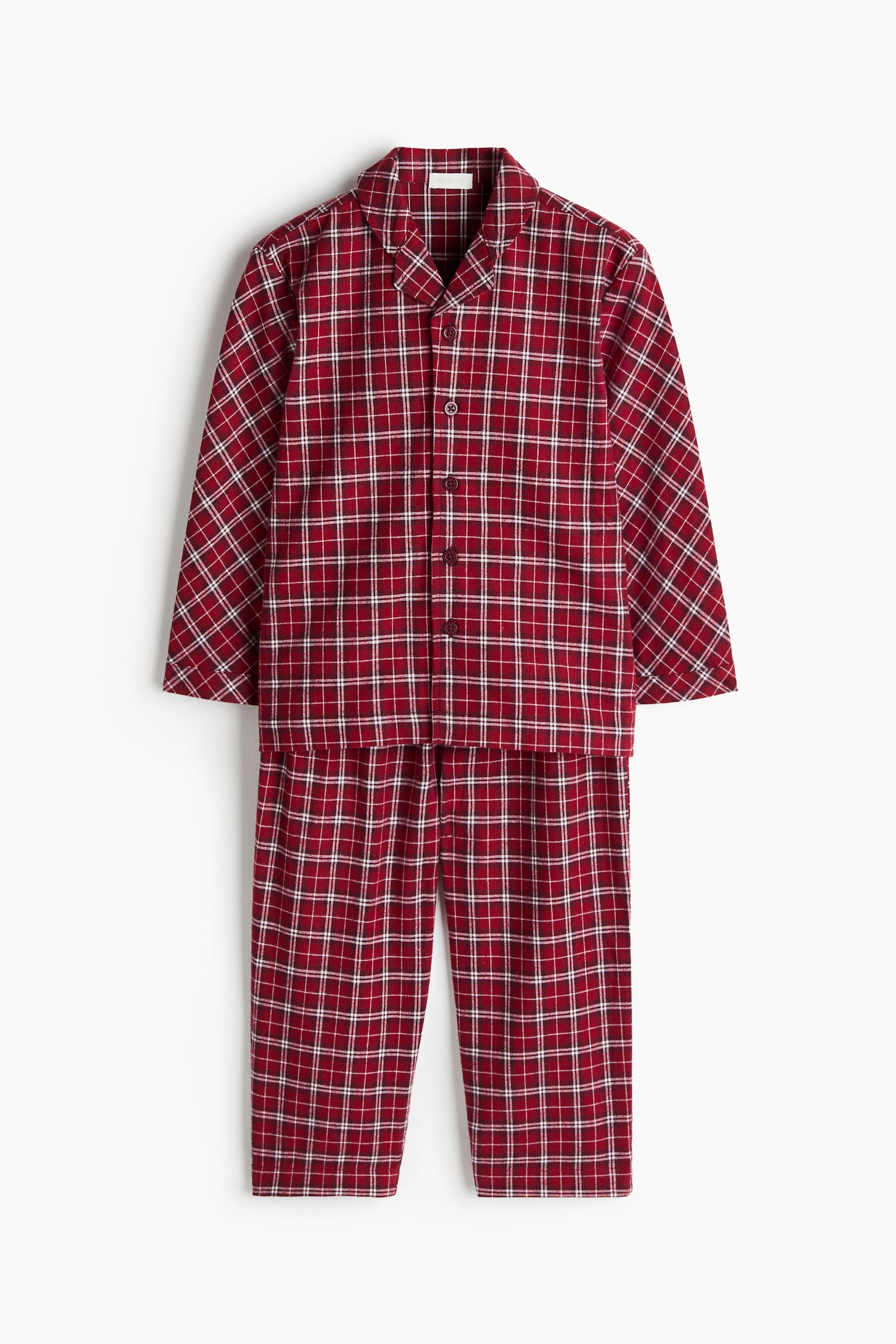 Un ensemble de pyjama deux piÃ¨ces Ã  motif Ã©cossais rouge et blanc est suspendu de face. L'ensemble met en valeur une chemise Ã  manches longues avec revers crantÃ©s et une fermeture boutonnÃ©e, accompagnÃ©e d'un pantalon assorti Ã  jambe droite.