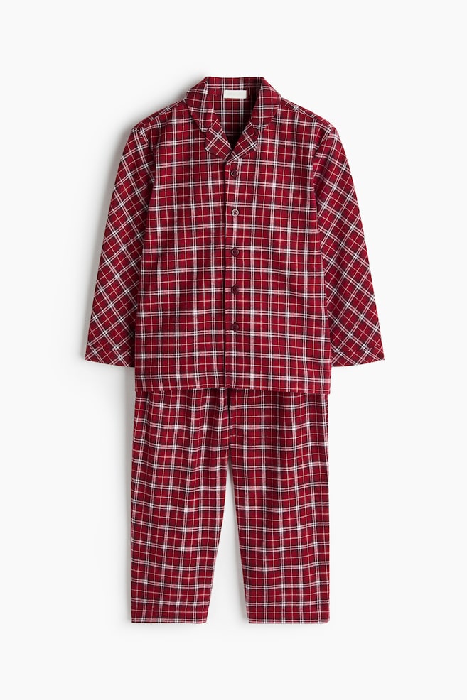 A two-piece pyjama set featuring a red and white plaid pattern is hanging facing front. The set showcases a long-sleeve shirt with notch lapels and a button-down fastening, alongside matching straight-leg trousers. - 1