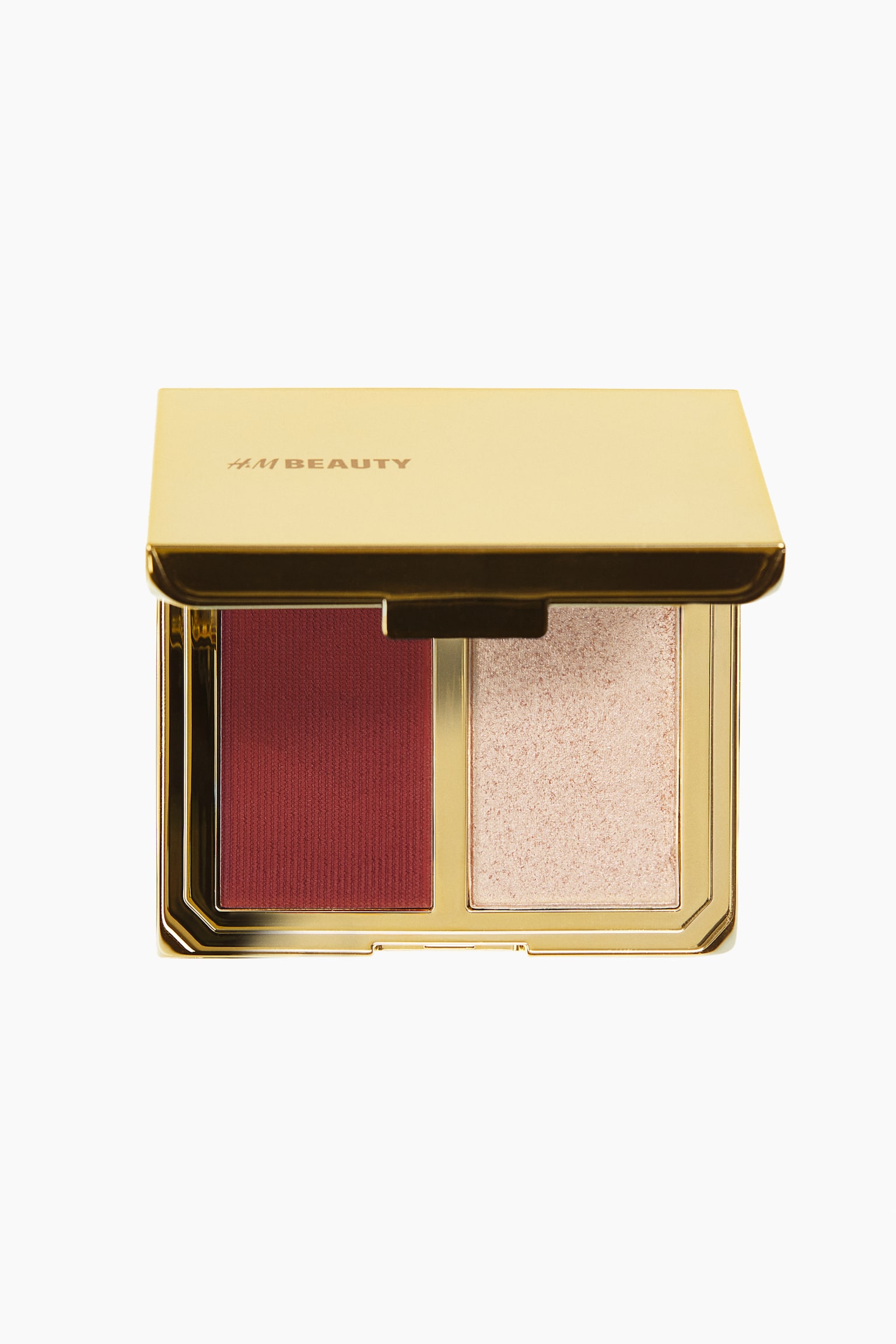 Facing front, a metallic gold makeup compact is standing open, displaying a deep burgundy powder blush with a finely textured surface on the left and a shimmering champagne-toned powder highlighter on the right. The raised lid is showcasing the brand name "H&M BEAUTY" in gold lettering.