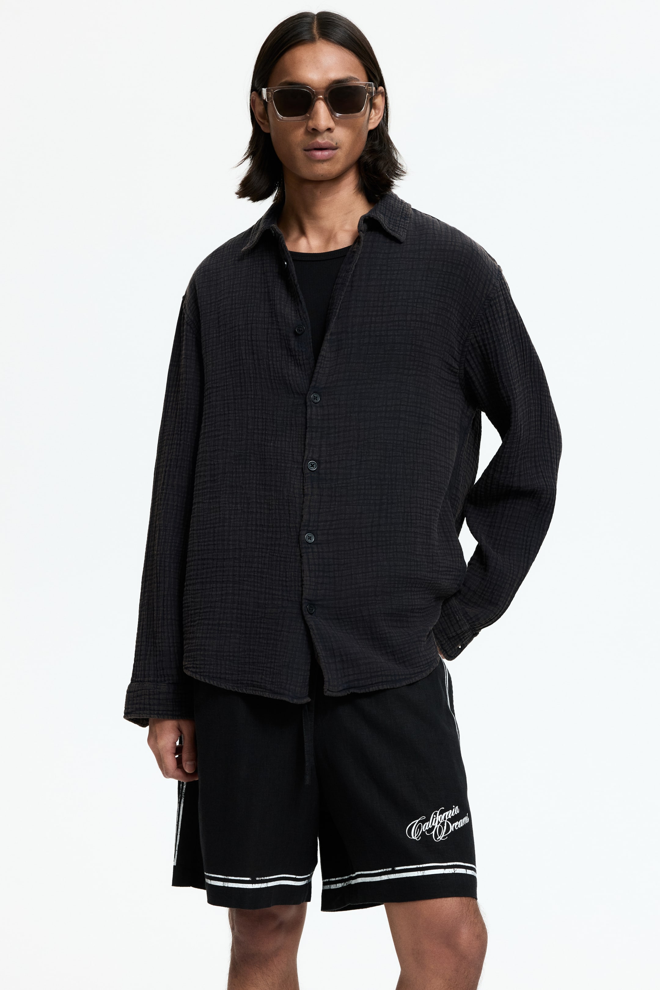 View larger image: A dark grey crinkled long-sleeve shirt features a relaxed fit with a collar and a button-down front. It is styled open over a black undershirt.