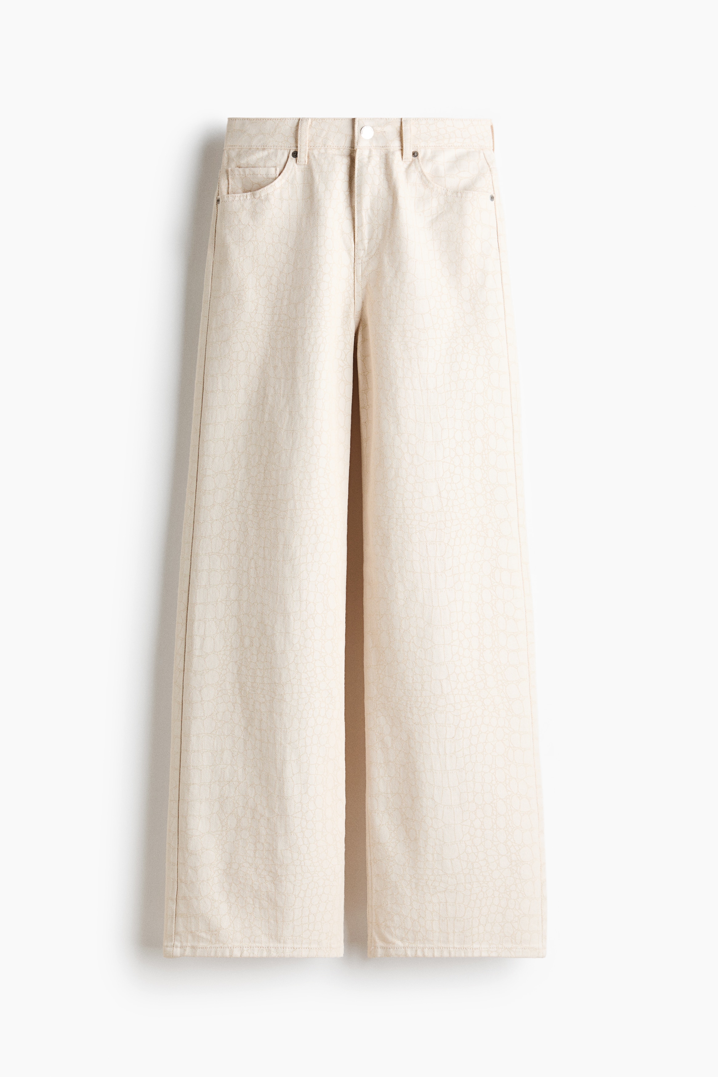 Los vaqueros denim de tiro alto en color blanco roto, con corte recto y diseÃ±o de cinco bolsillos, los lleva puestos la modelo. Los vaqueros se combinan con una camiseta blanca metida parcialmente por dentro y zapatillas blancas.