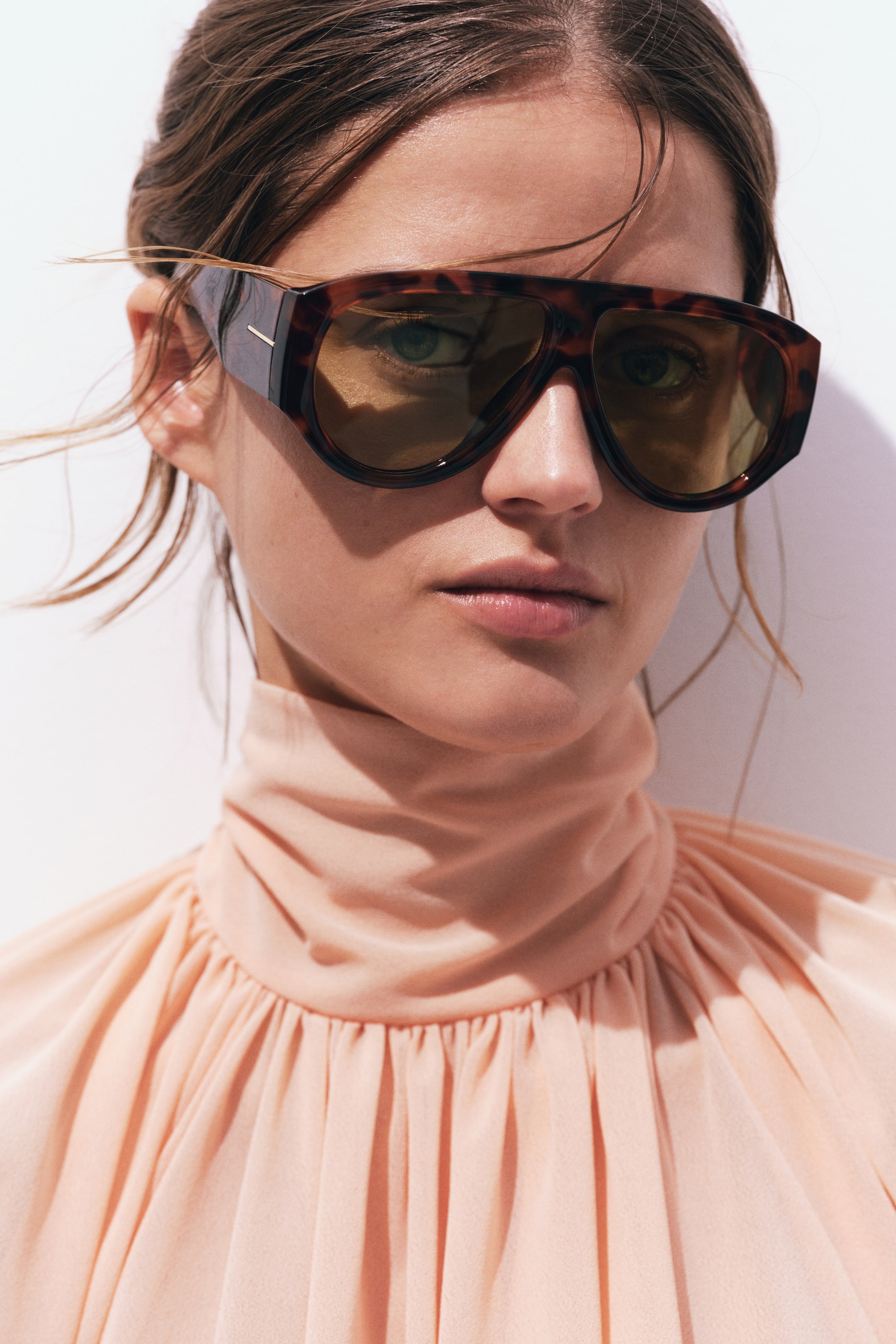View larger image: Oversized tortoiseshell sunglasses are being worn, featuring a wide, flat-top frame and amber-tinted lenses. A small horizontal metallic detail adorns the left temple.