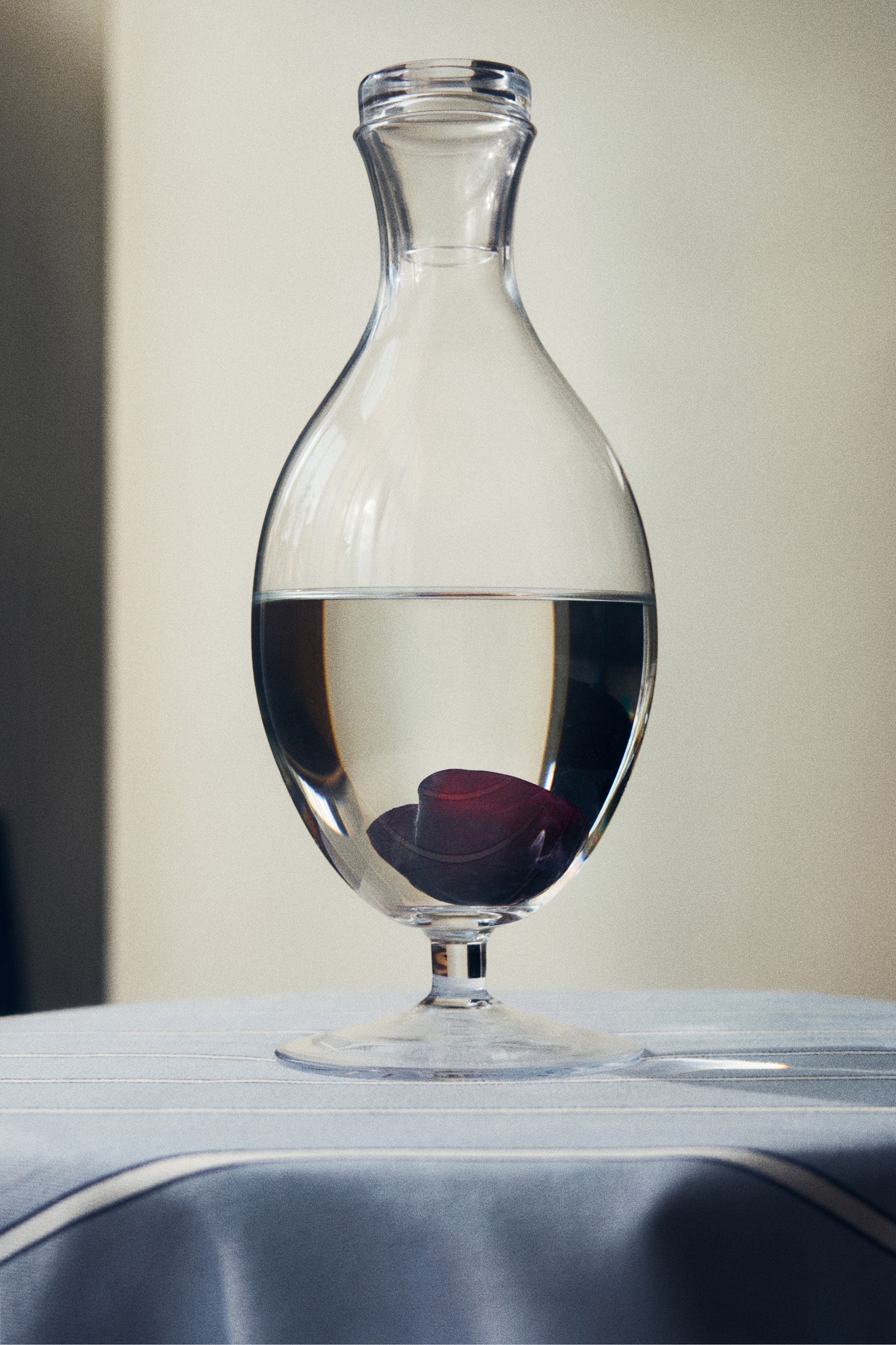 View larger image: A delicate clear glass footed wine decanter is shown from the front. It features a rounded body tapering into a slender neck, and is supported by a clear glass foot.