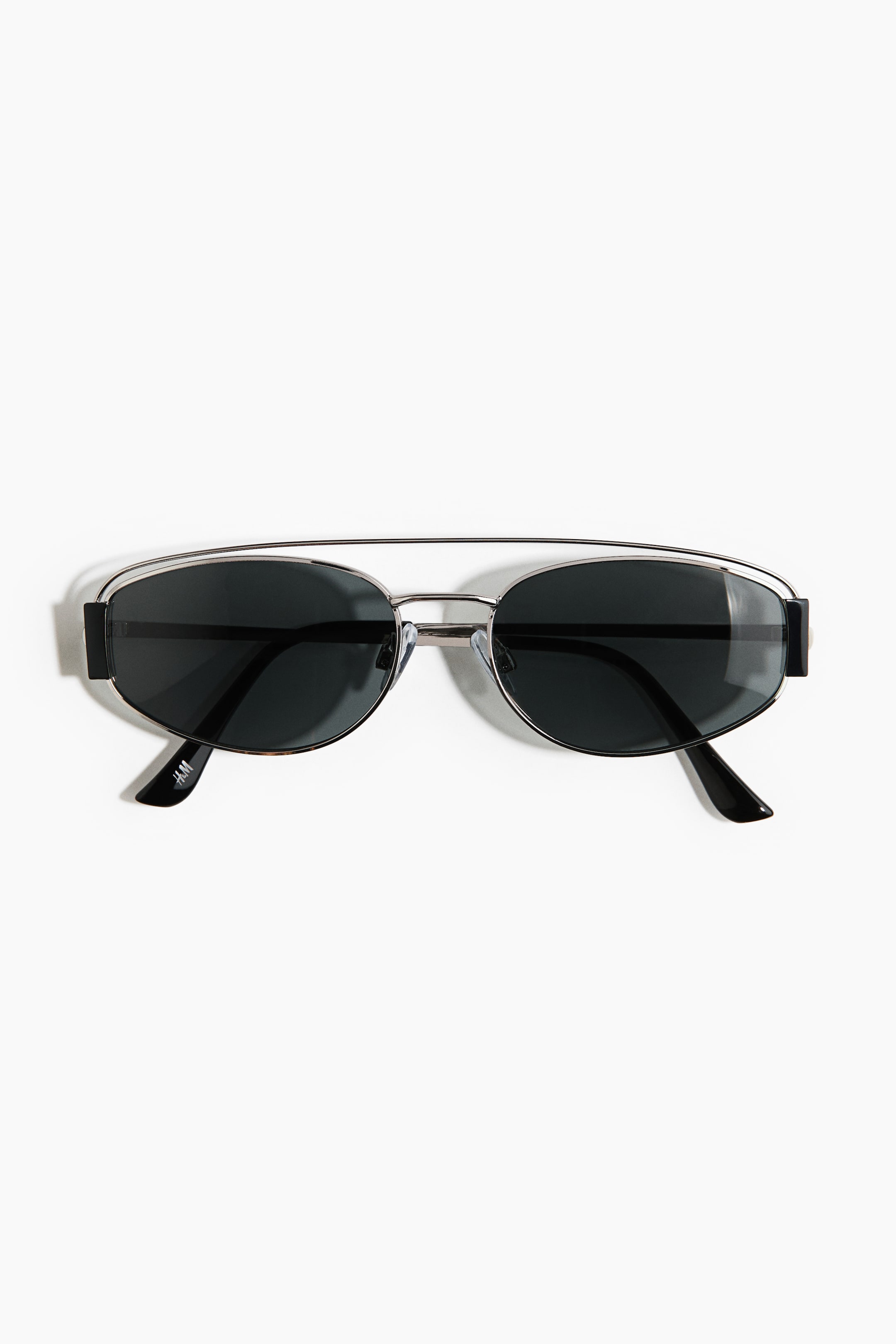 View larger image: Oval sunglasses are shown from the front, featuring dark, UV-protective polarized lenses set in silver-toned metal frames. They are designed with adjustable nose pads and metal sidepieces that transition into black plastic temple tips.