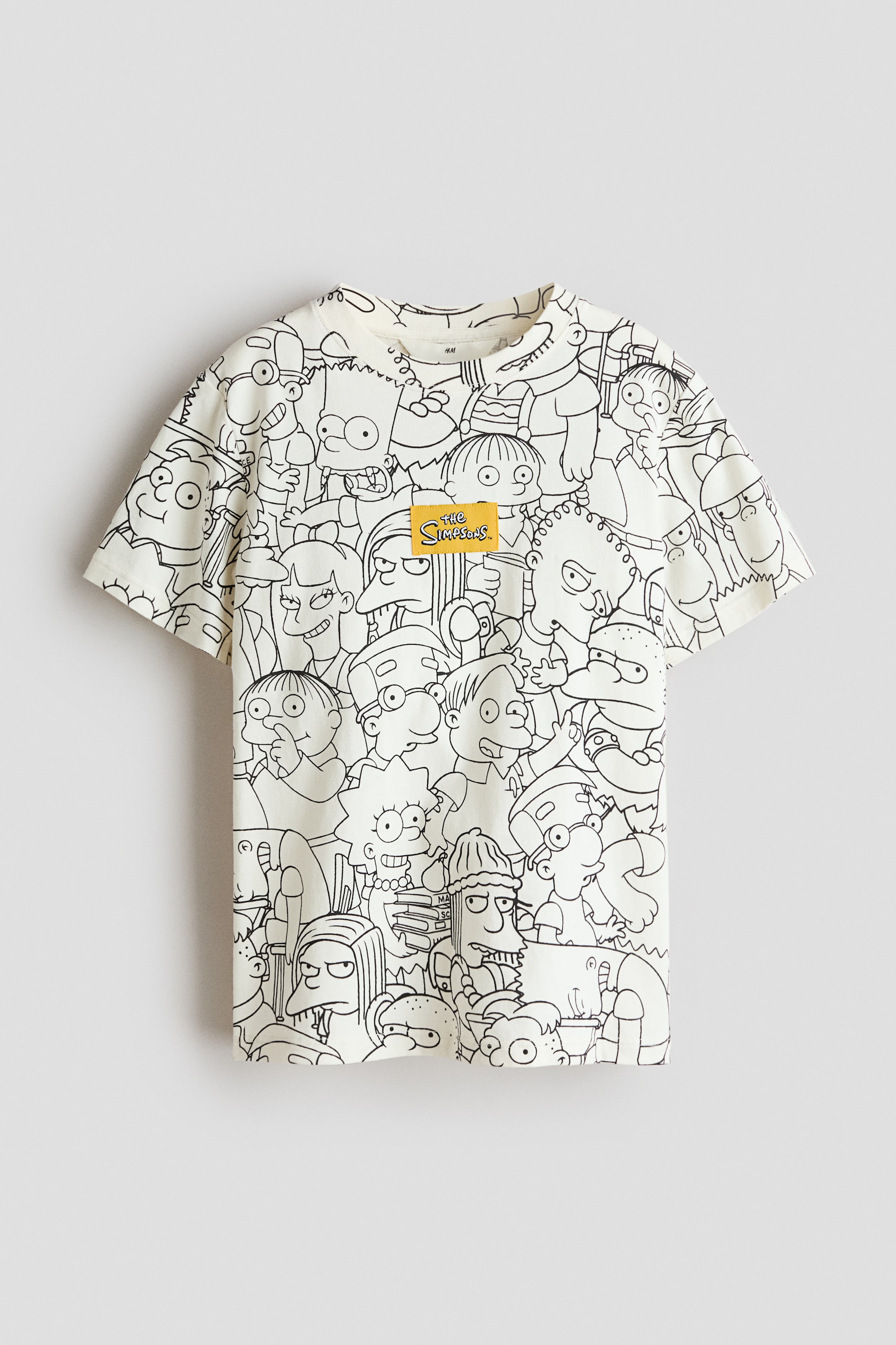 View larger image: This short-sleeved t-shirt showcases an all-over black outline print of various characters from The Simpsons on its cream-coloured fabric. Centrally placed on the chest is a small yellow woven patch featuring "The Simpsons" logo.