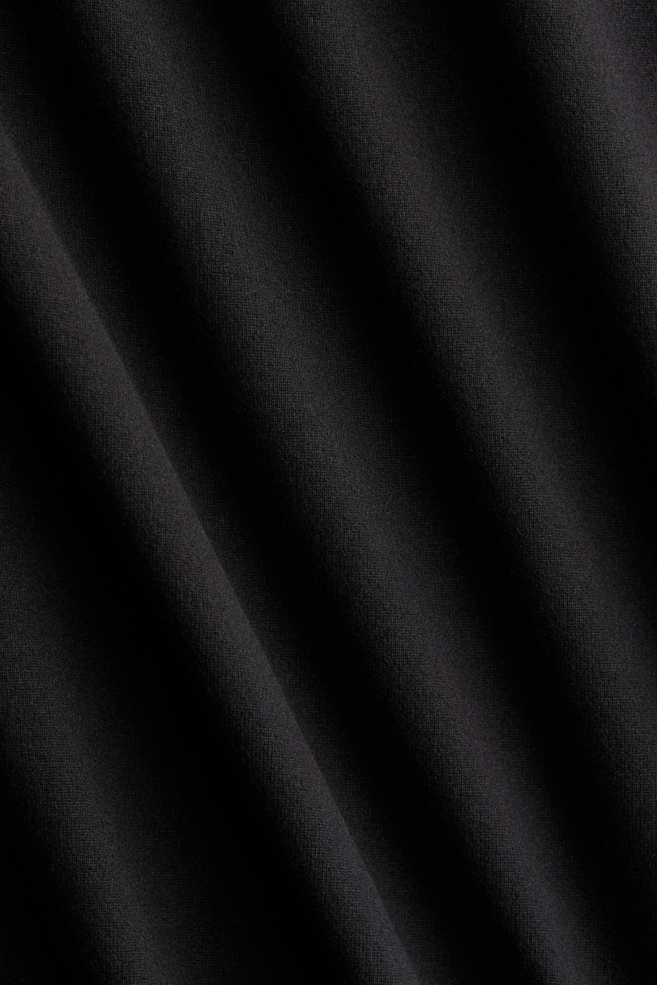 Grotere afbeelding bekijken: De licht geborstelde jersey van de lange, nauwsluitende jurk toont een diepzwarte kleur met zachte, subtiele plooien en een fijne, egale textuur.