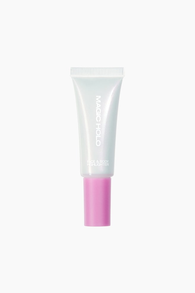 Um tubo de iluminador para rosto e corpo está em pé na FRENTE, apresentando um corpo branco perolado com um tom azul claro e uma tampa rosa sólida. O tubo exibe "MAGIC HOLO" impresso verticalmente e "FACE & BODY HIGHLIGHTER" impresso horizontalmente. - 1