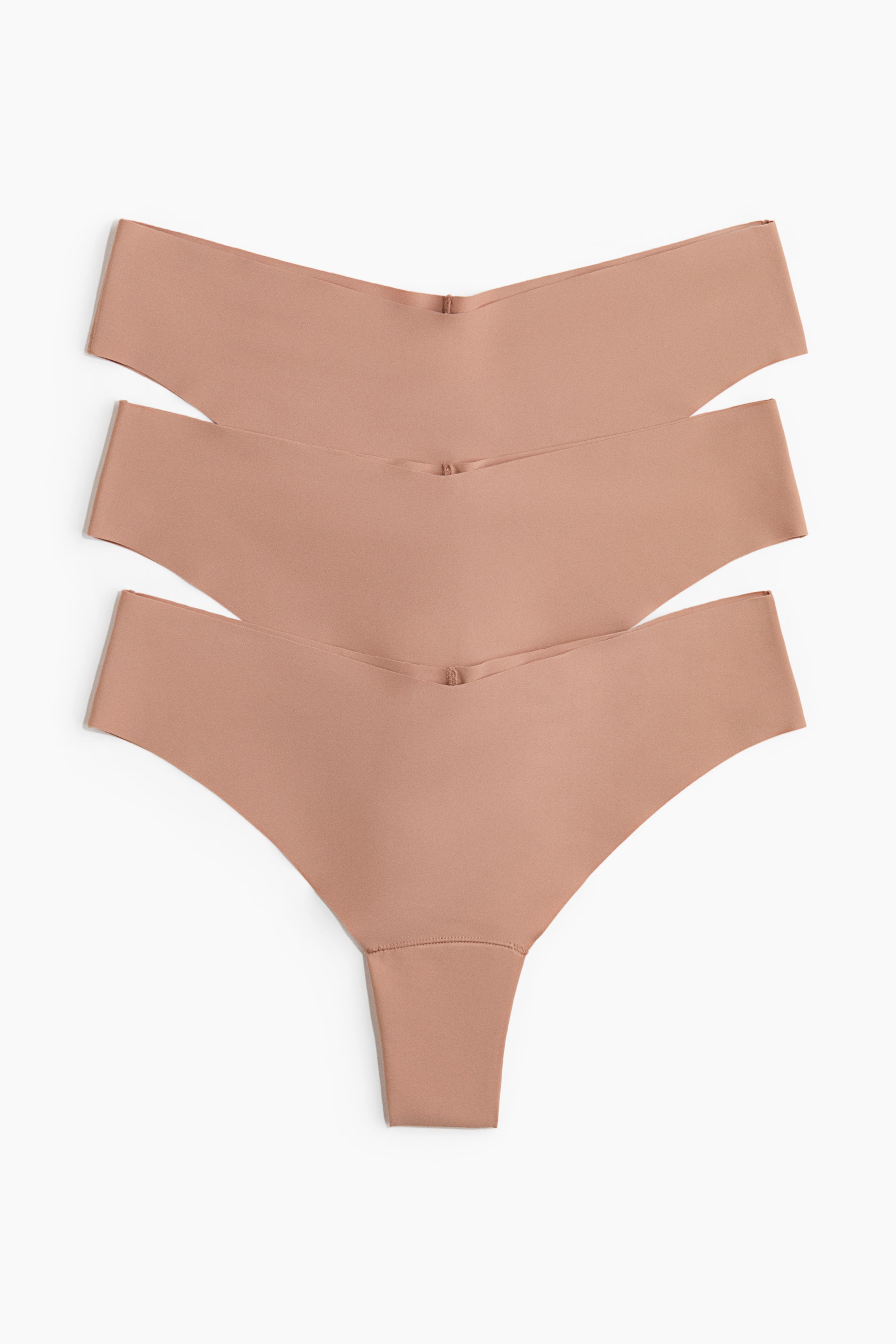 Grotere afbeelding bekijken: Drie lichtbruine slips worden aan de voorkant getoond, gelaagd op elkaar. Elke slip heeft een lage, V-vormige tailleband en naadloze laser-cut randen, wat de gladde microvezelconstructie benadrukt met een smalle, hoog uitgesneden achterkant die zichtbaar is op de onderste slip.