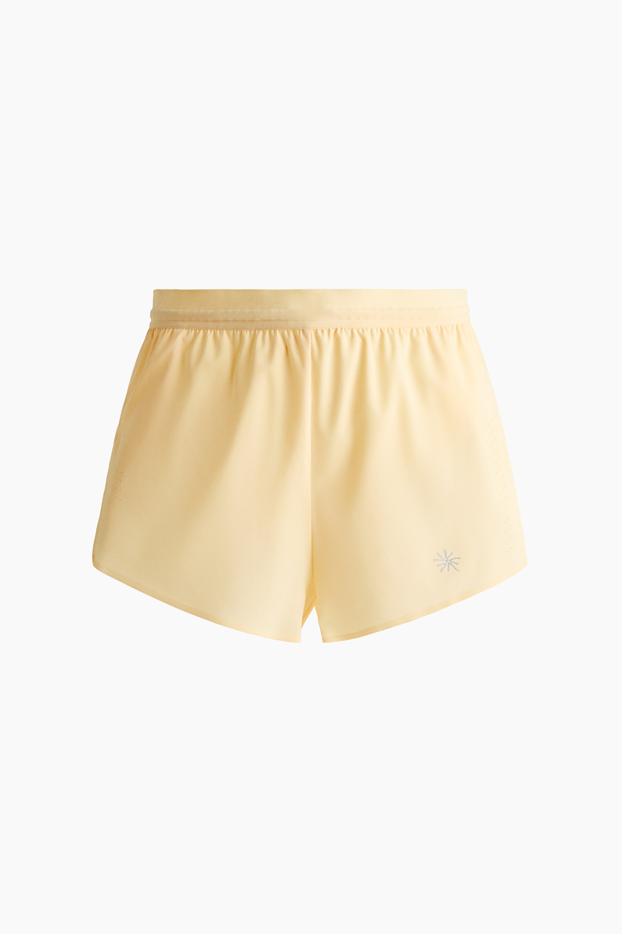 Visualizza immagine più grande: Un paio di pantaloncini da corsa corti giallo chiaro è mostrato frontalmente, caratterizzato da una fascia elastica coperta in vita, un piccolo logo riflettente a forma di stella sulla gamba sinistra e sottili spacchi sui bordi laterali.