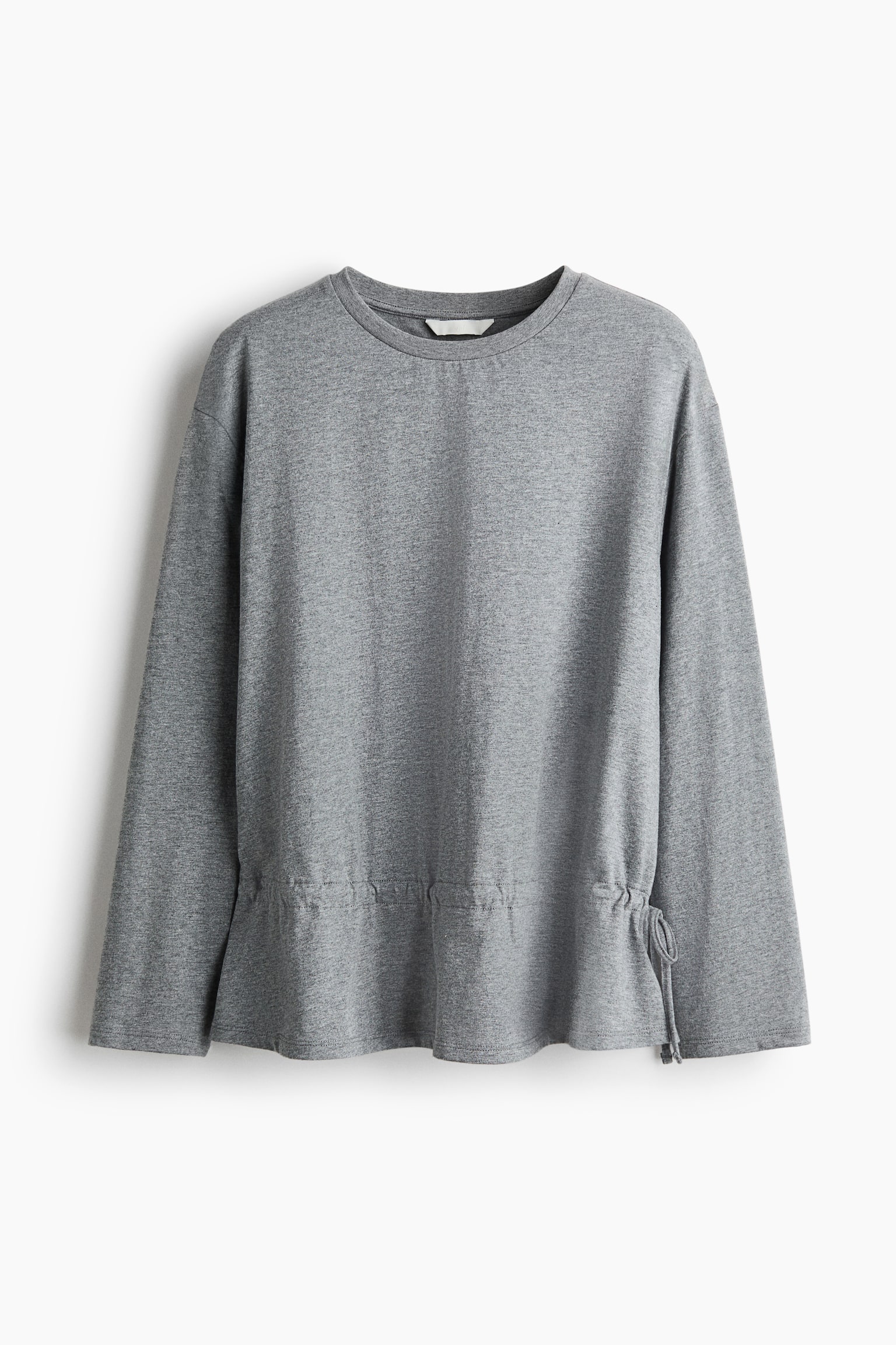 A heather grey long-sleeve top is shown from the front, featuring a crew neckline and relaxed long sleeves. The top is gathered above the hem with an adjustable drawstring that ties at the side, creating a subtly flared peplum shape.