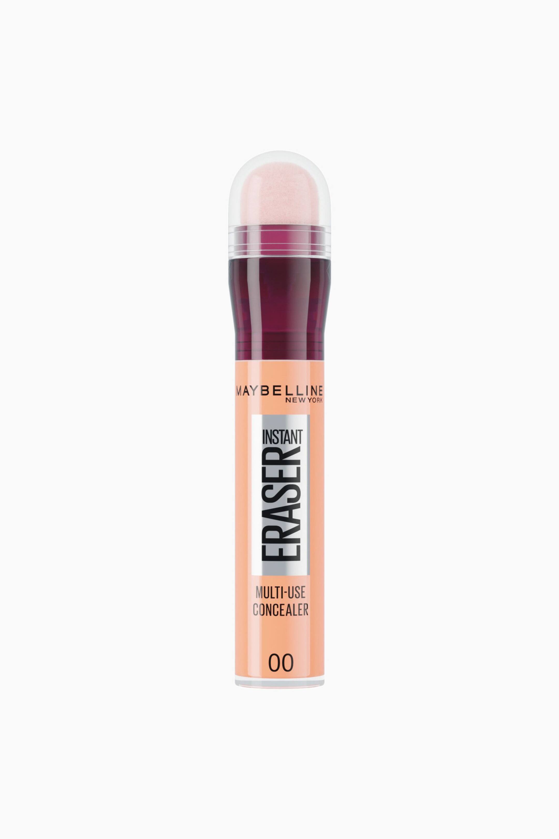 Se større billede: En Maybelline Instant Eraser Multi-Use Concealer står oprejst og vender fremad, så den ferskenfarvede formel kan ses inde i et cylindrisk hylster. Hylstret har sort og sølvfarvet branding under en dyb bordeauxfarvet krave og en gennemsigtig kuppelformet hætte, der dækker en lyserød svampeapplikator.