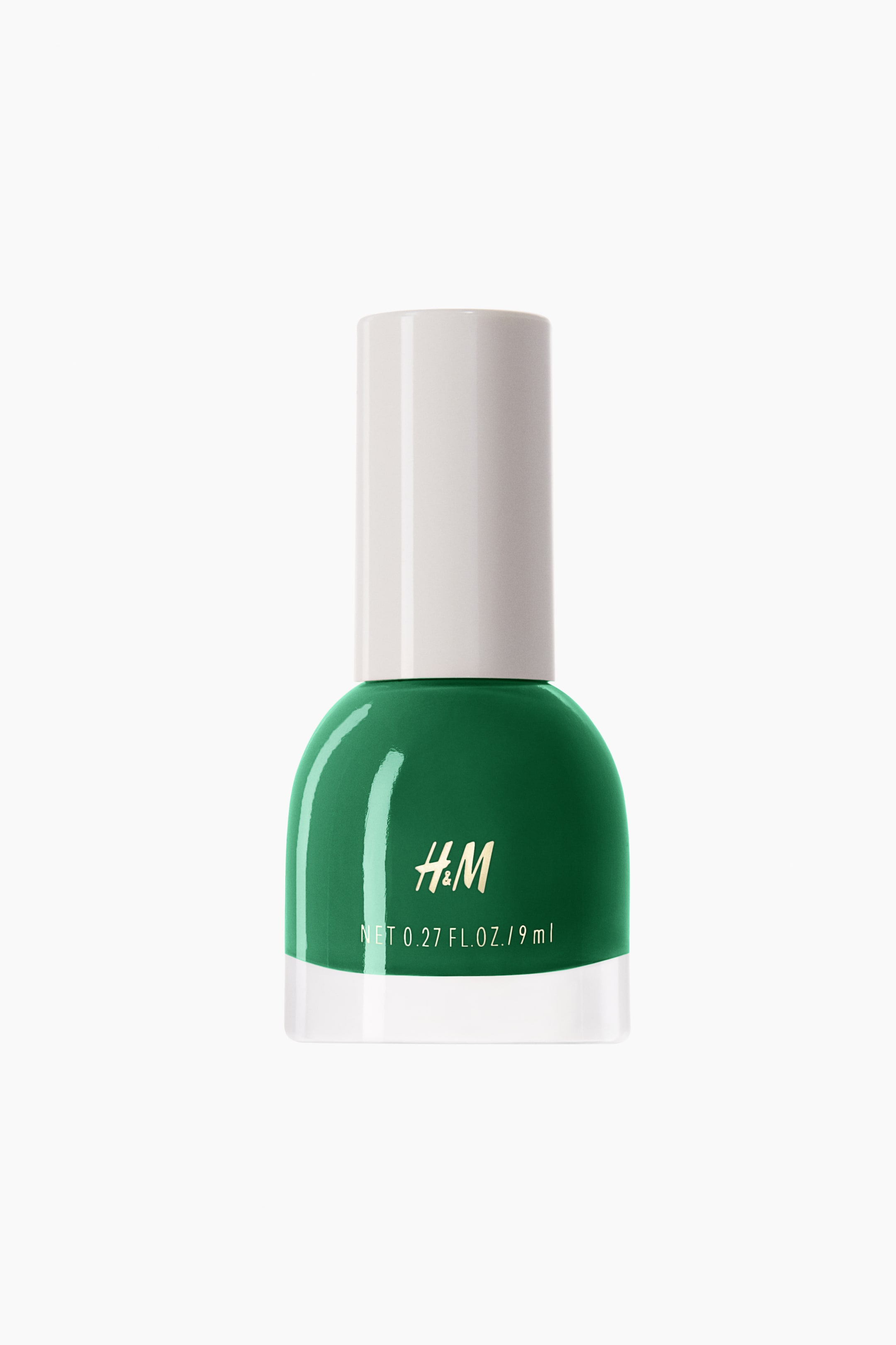 View larger image: An emerald green nail polish bottle is standing upright, facing forward, featuring a glossy finish and a white cylindrical cap. The bottle is displaying the H&M logo and "NET 0.27 FL. OZ. / 9 ml" in gold text on its front.
