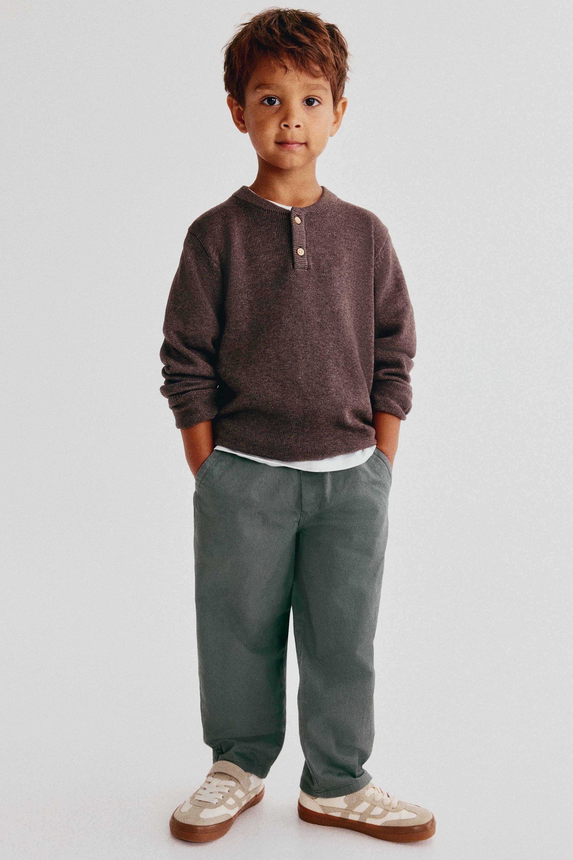 The sage green pants feature an elasticated waistband with a central drawstring and two side slash pockets. They present a straight-leg cut, viewed from the front.