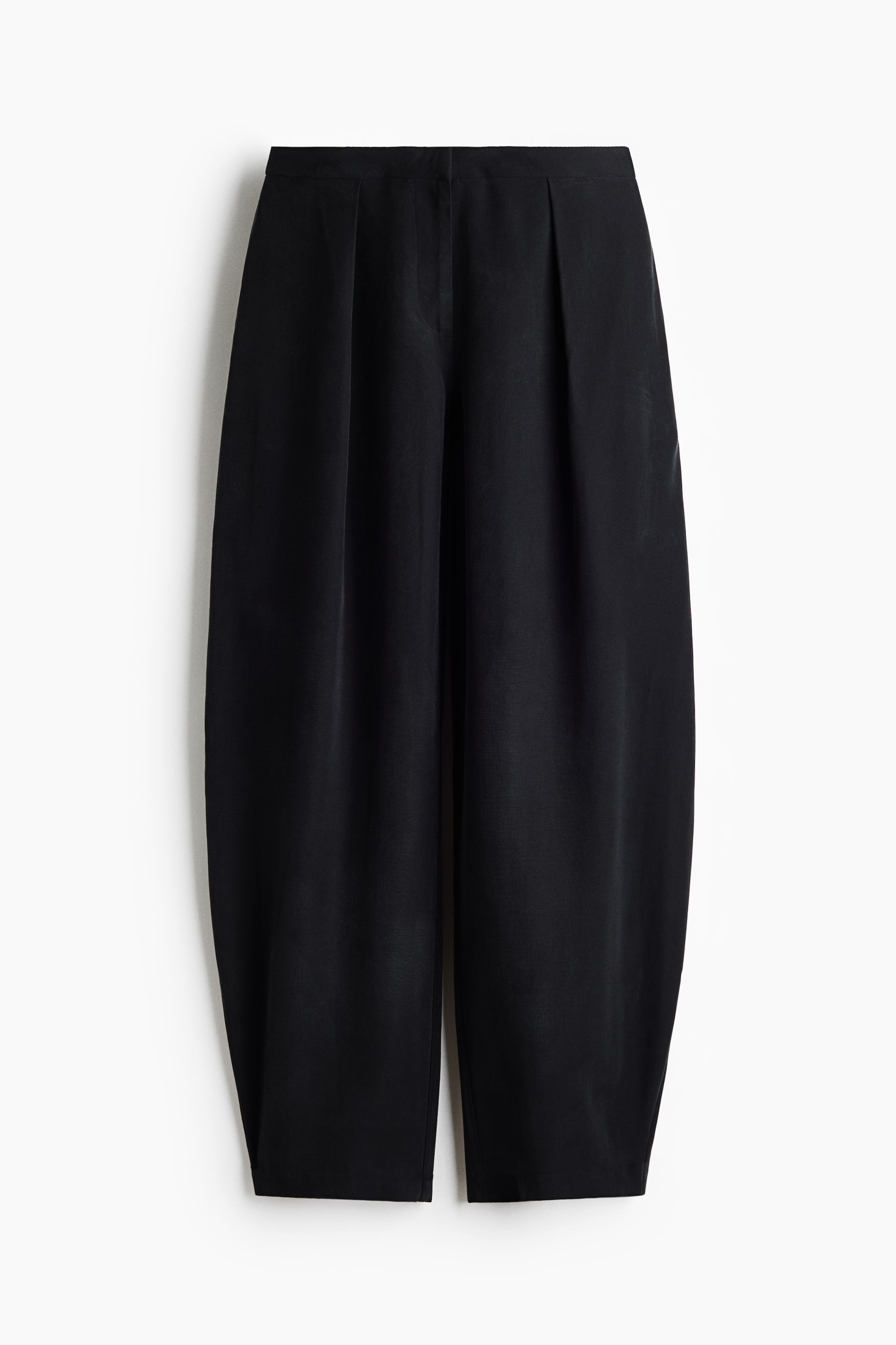 View larger image: The black trousers are displayed from the front, showcasing a flat waistband and two distinct front pleats. The wide legs create a rounded, voluminous silhouette, finishing with a straight, cropped hem.