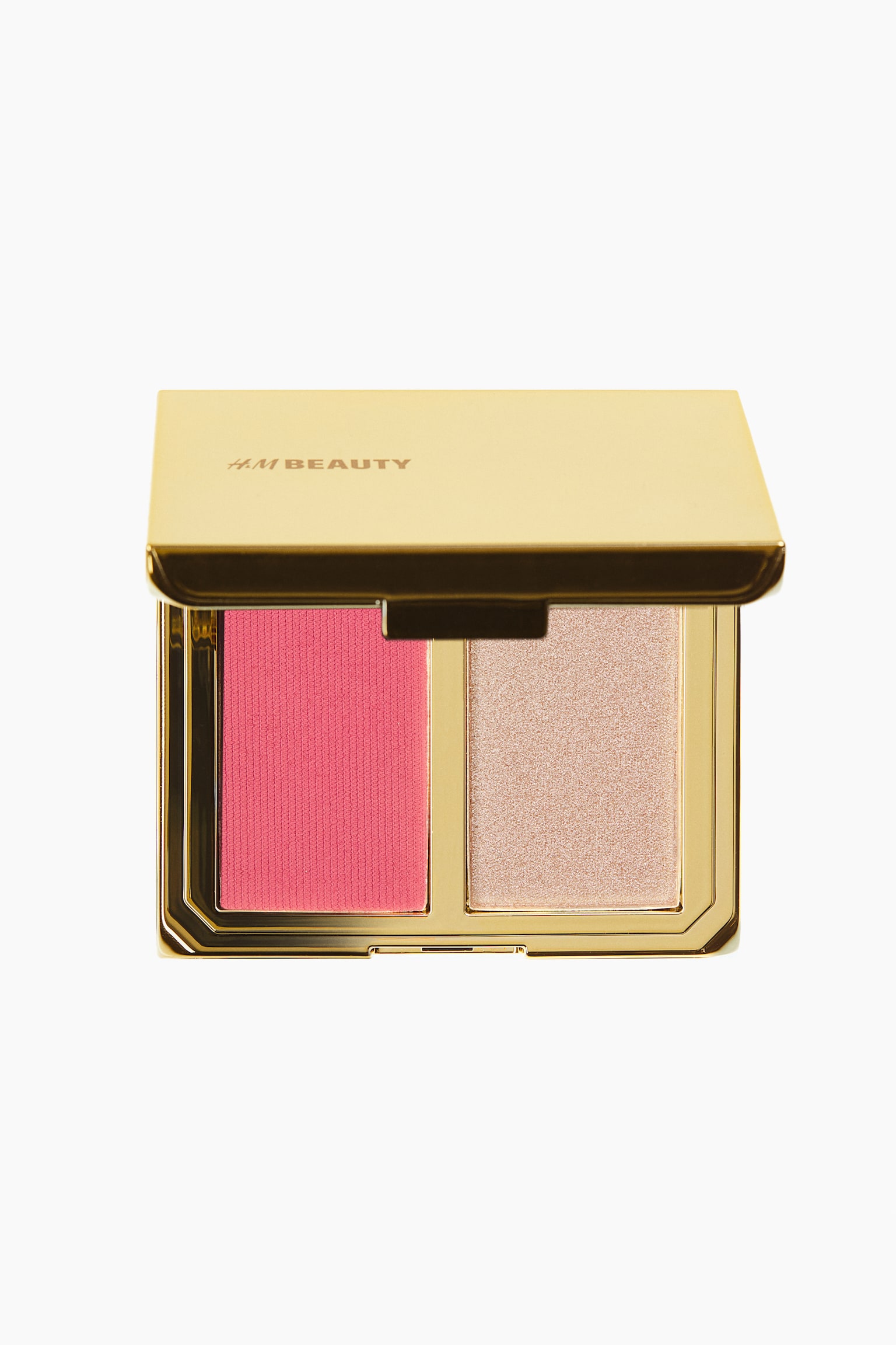 An open, gold-toned makeup compact is facing front, showcasing a two-pan palette that contains a vibrant pink blush on the left and a shimmery champagne-coloured highlighter on the right. The metallic gold lid is displaying the brand name "H&M BEAUTY" in debossed lettering.