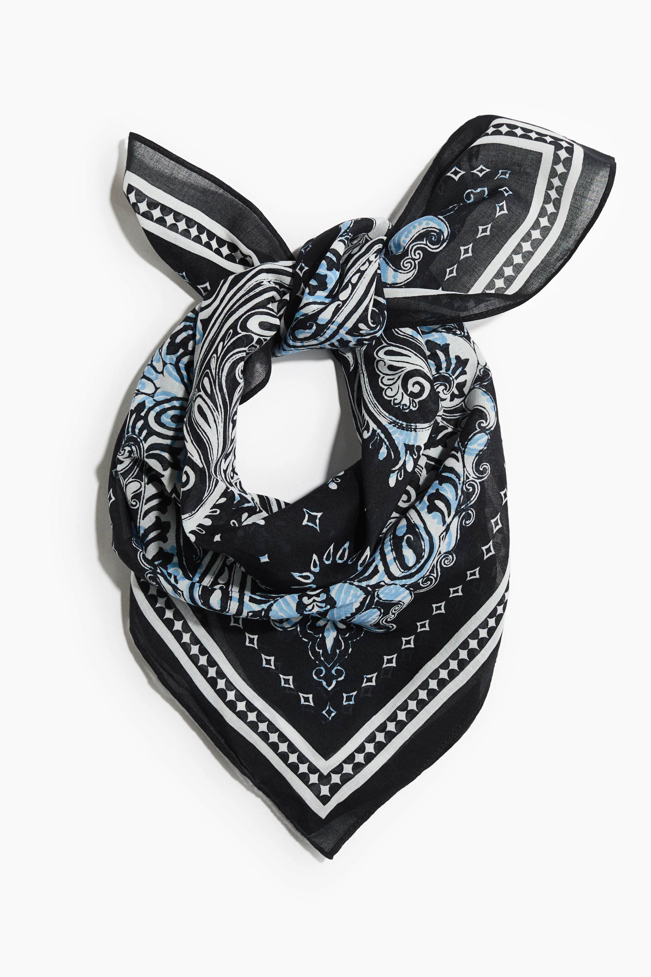 Agrandir l'image: Un bandana noir présente un motif cachemire blanc et bleu clair. Il se distingue par une bordure distincte de lignes blanches et de formes géométriques, et est noué en un nœud au sommet.