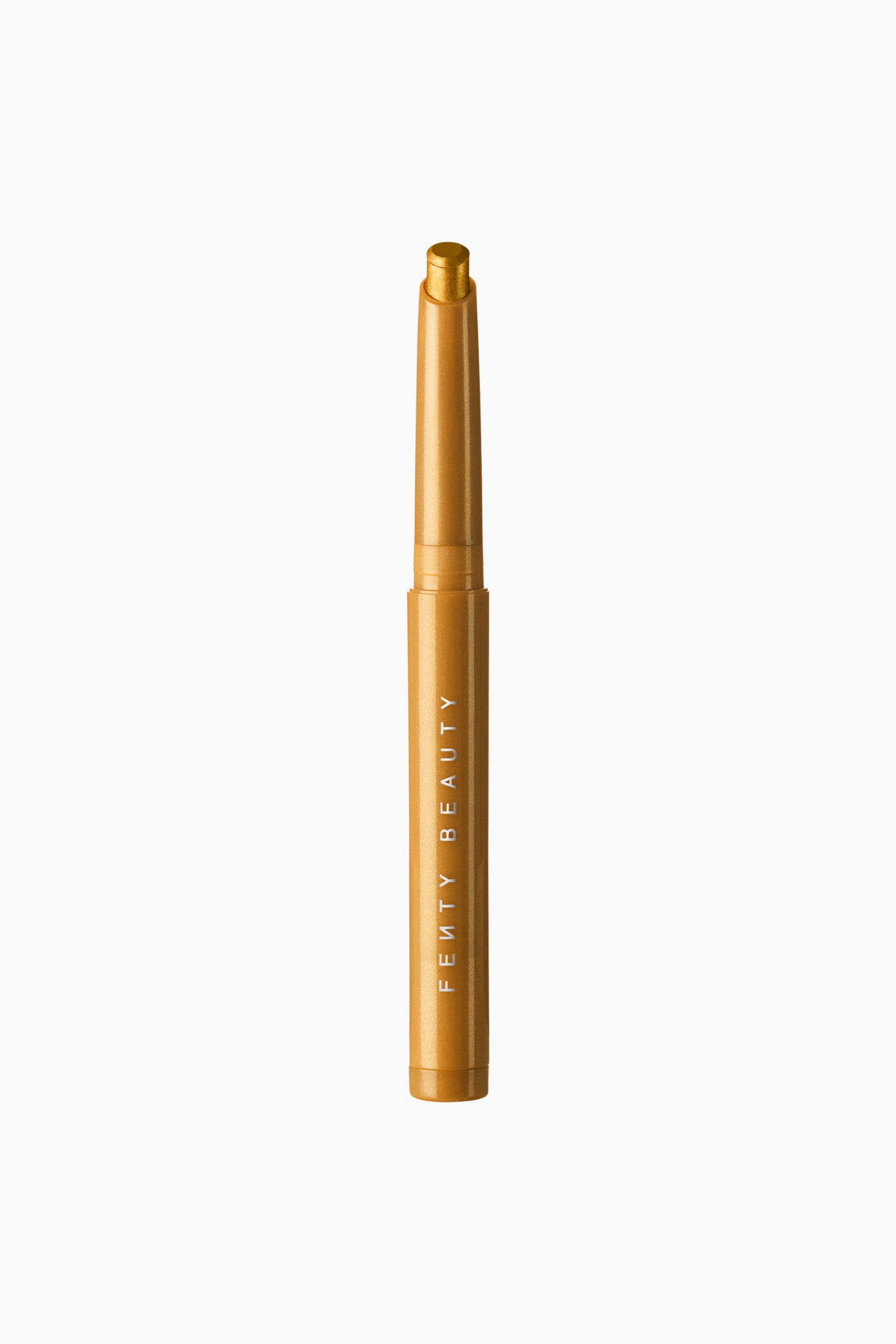 Se større billede: Shadowstix Longwear Eyeshadow Stick står lodret og fremviser en slank, metallisk guldfarvet hylster med brandnavnet "FENTY BEAUTY" trykt lodret i hvidt. Det uden låg viste produkt afslører en afrundet, metallisk gylden øjenskyggetip, der stikker op fra toppen.
