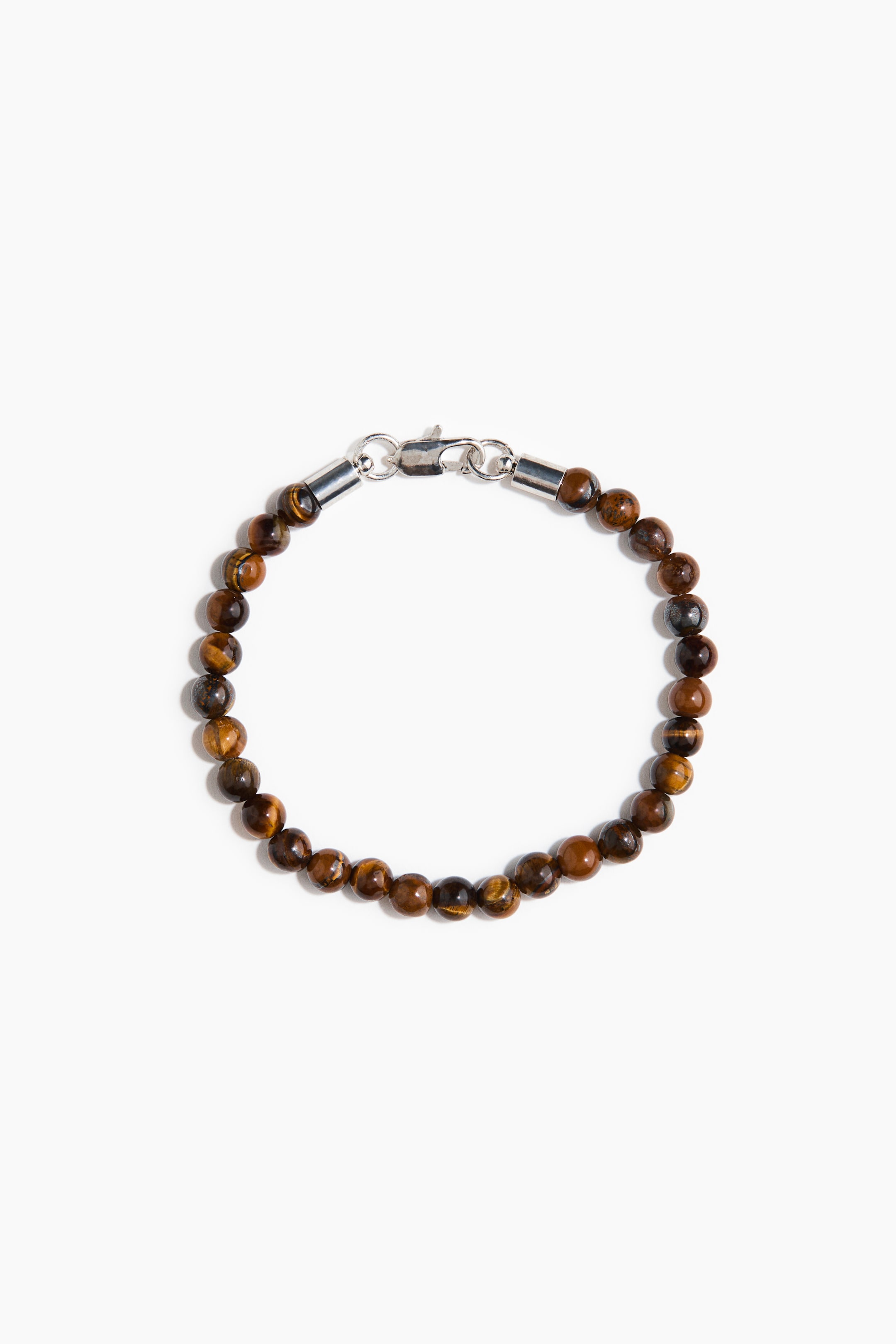 View larger image: The bracelet features round, brown and golden tiger's eye beads and displays a silver-toned lobster clasp with two cylindrical end caps.
