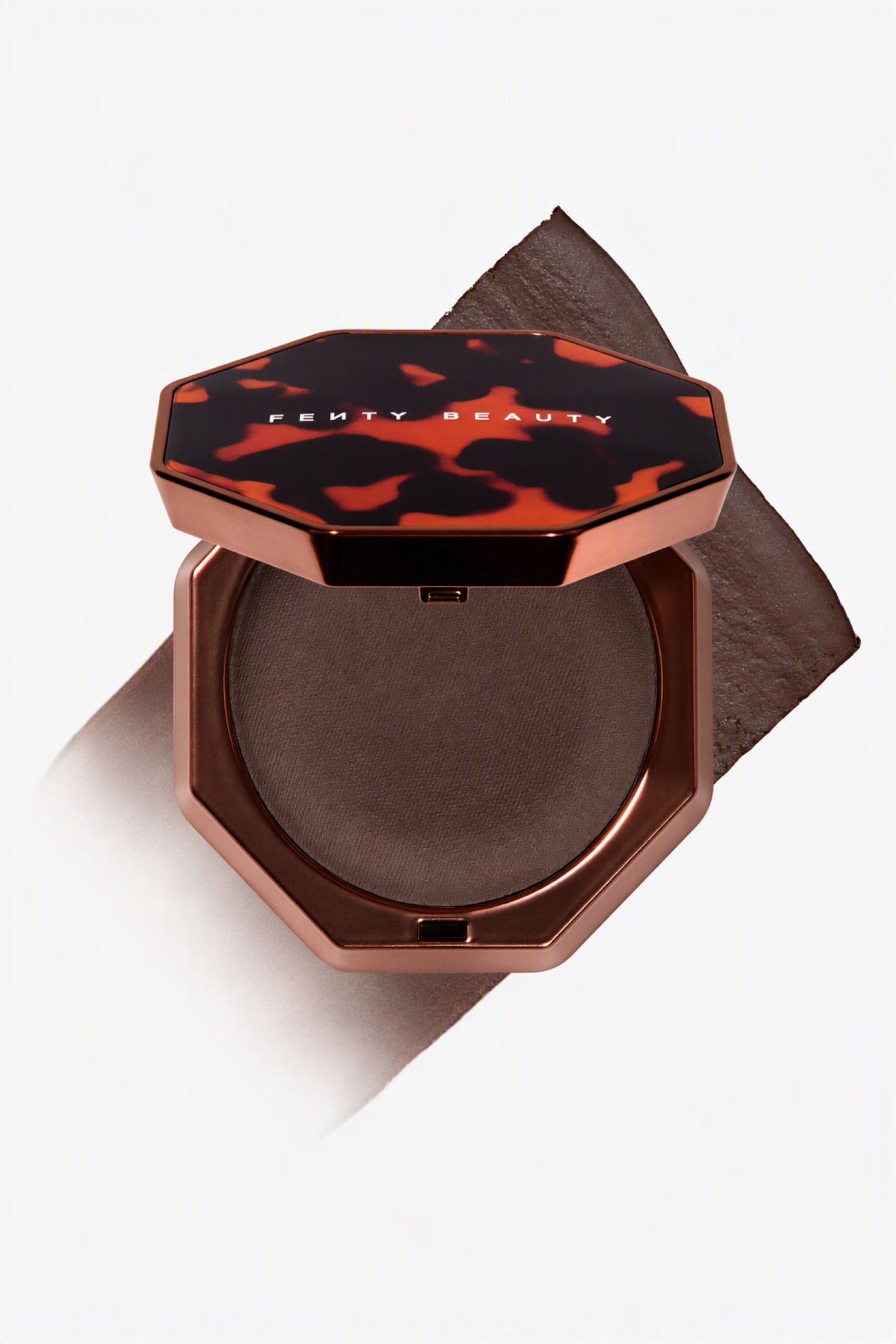 Visa större bild: En öppen, åttkantig kompakt i metallisk brons visar en djupbrun pressad bronzer i en rund pan när den vilar över ett diagonalt, texturerat prov av den matchande nyansen. Det delvis uppfällda locket visar ett svart och bärnstensfärgat sköldpaddsmönster med varumärkesnamnet tryckt i vitt över mitten.
