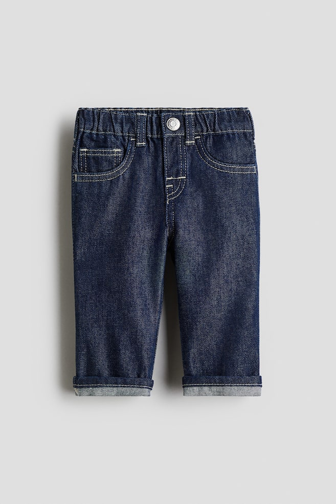 A pair of dark blue denim jeans is presented facing forward. It is featuring an elasticated waistband with a metal button, two curved front pockets with a smaller coin pocket, and prominent light-colored contrast stitching. The straight legs are visibly cuffed at the bottom. - 1