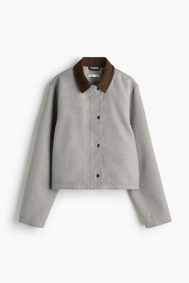 Une veste à motif pied-de-poule est présentée de face, avec un col en suédine marron foncé. Elle est fermée par trois boutons-pression sombres sur le devant et présente des manches longues avec un ourlet court. - 1