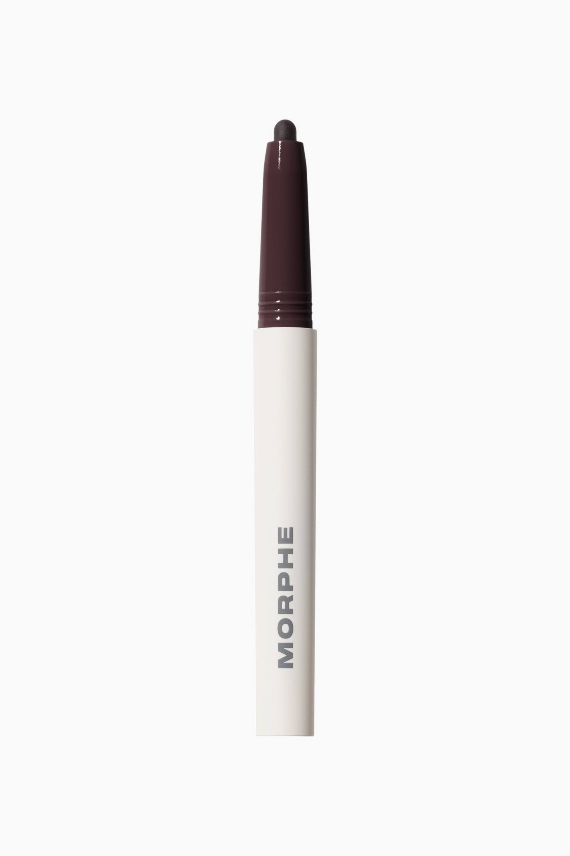 Visa större bild: Sculptwear Signature Lip Pencil står upprätt och har en mattvit hylsa med varumärkesnamnet ”MORPHE” tryckt vertikalt i grått. Den övre delen smalnar av till en mörkt plommonfärgad hals och en rundad, exponerad penntipp i samma djupa plommonnyans.