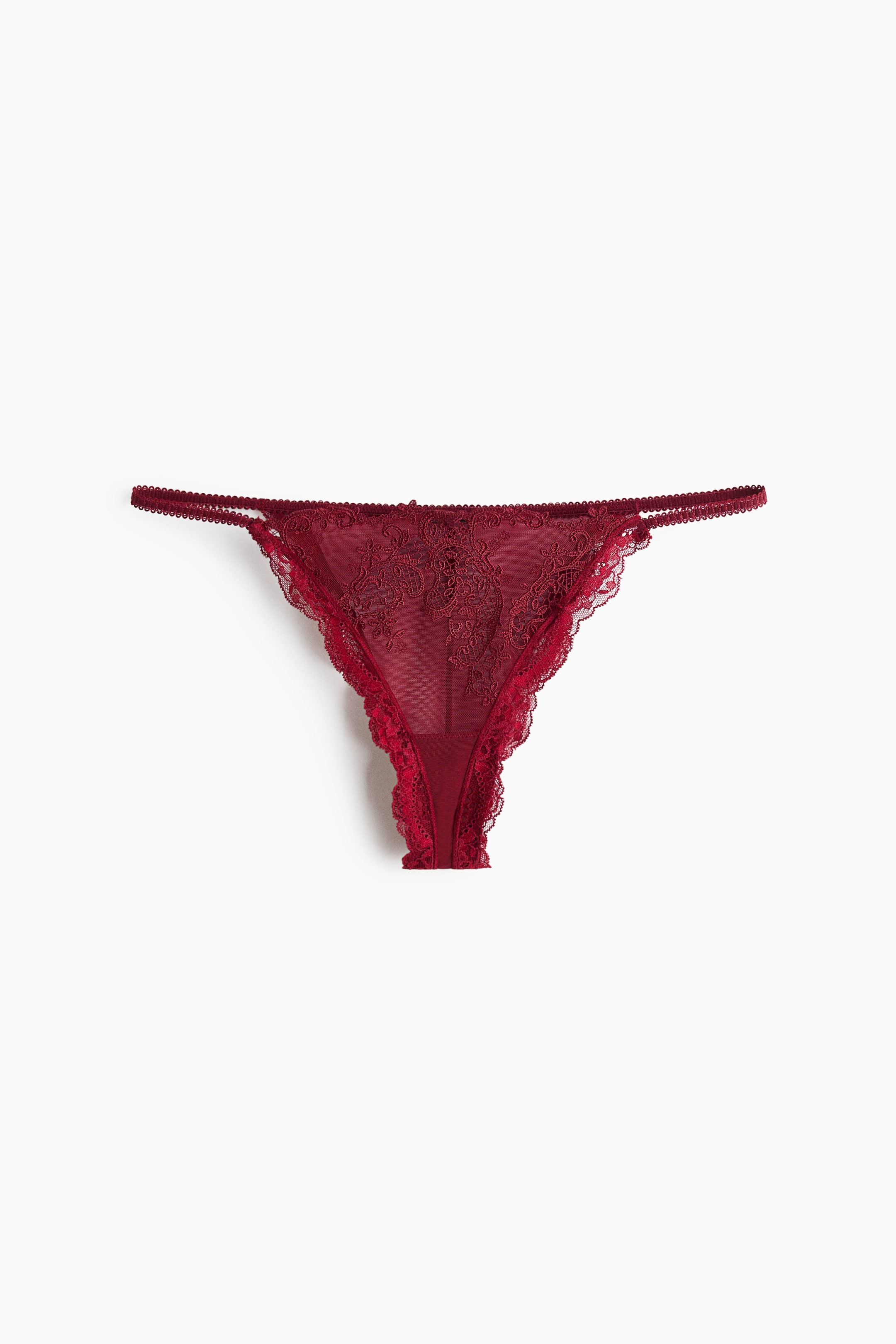 Visualizza immagine più grande: Un tanga in pizzo color bordeaux è mostrato frontalmente, con un pannello anteriore triangolare in rete trasparente e ricami floreali intricati. Il design presenta sottili cinturini laterali elastici e un delicato bordo in pizzo smerlato lungo le aperture delle gambe.