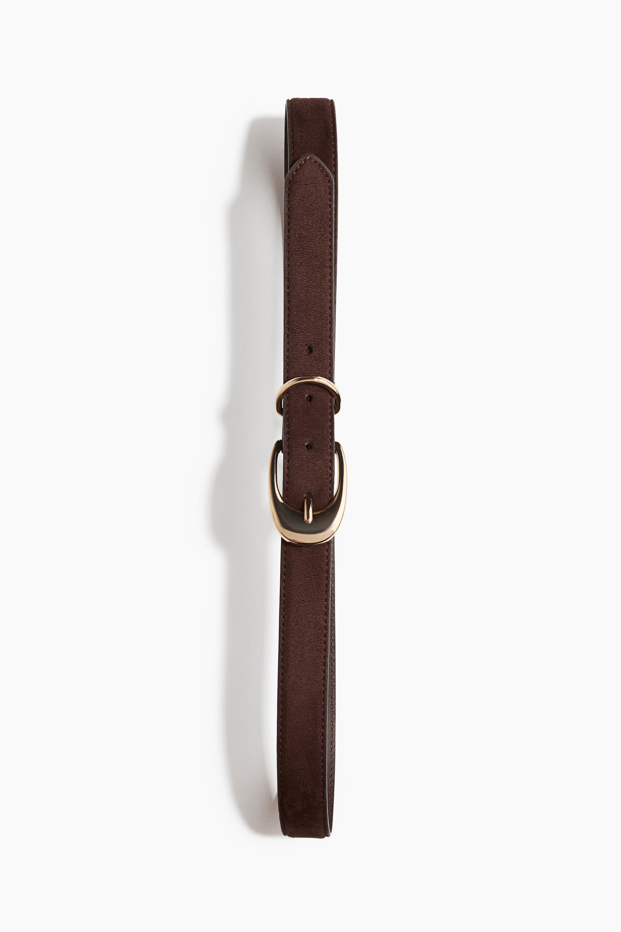 View larger image: A dark brown suede belt is laid vertically, showcasing a gold-toned, rounded buckle with a single prong and a matching keeper loop. The stitching is visible along the edges of the belt strap.