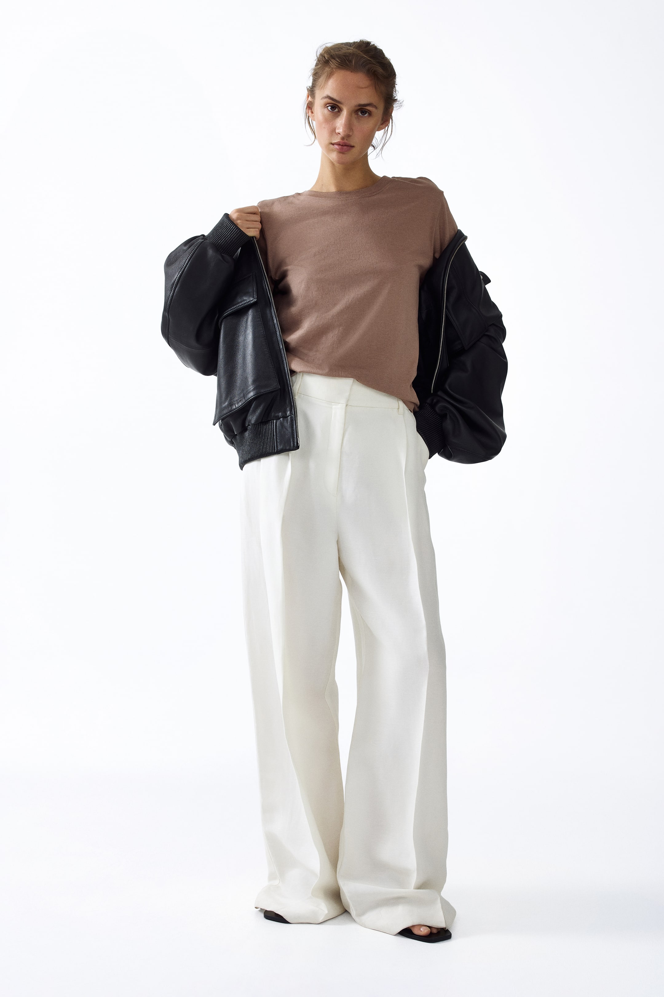 View larger image: White wide-leg pants featuring a high waist, visible as a brown top is tucked in. The pants are designed with a loose, flowing fit, a prominent front crease, and are pooling over black sandals.