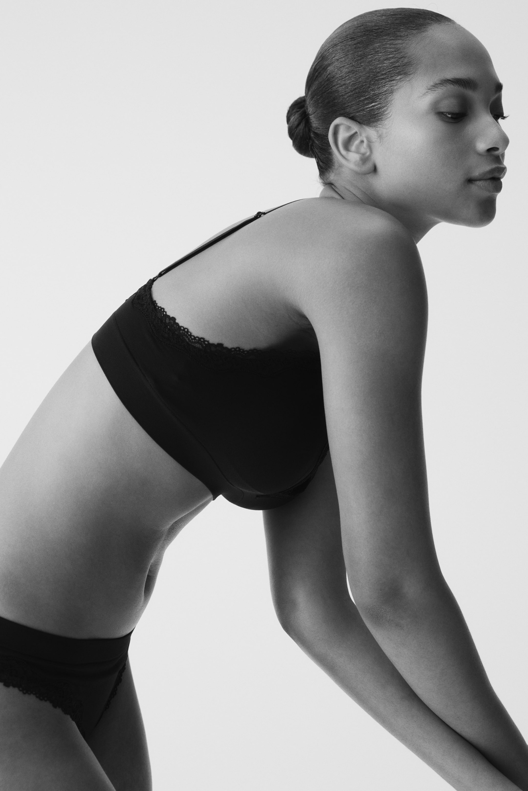 Voir une image plus grande: Un soutien-gorge noir sans armatures avec des bretelles réglables et une bordure en dentelle autour du haut est porté par le mannequin, s'ajustant parfaitement contre la peau.