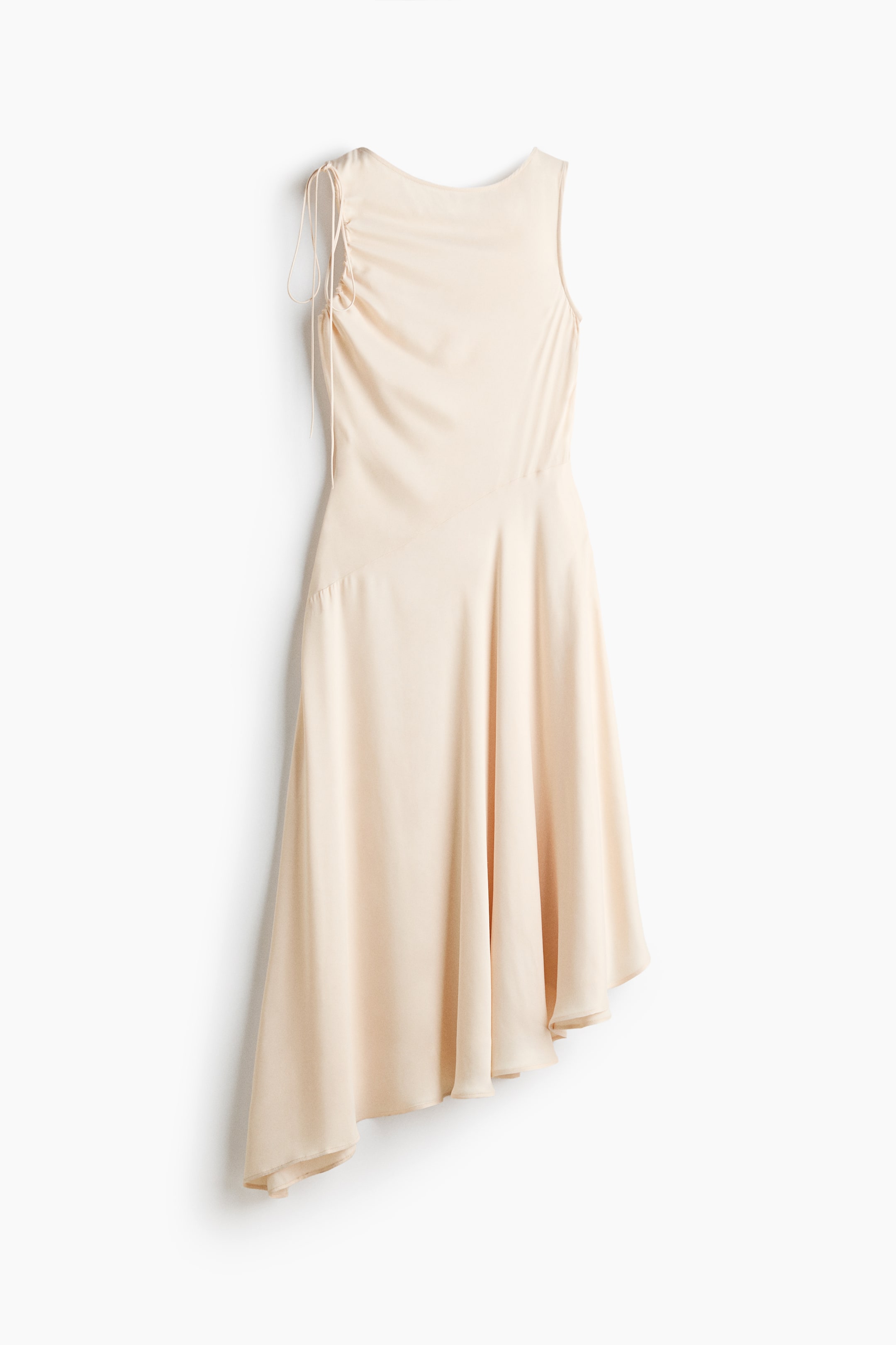 View larger image: The light beige dress features a sleeveless design with a round neckline. Ruched detailing with drawstrings is present on the left shoulder, and an asymmetrical midi-length skirt flows gracefully from the waist.
