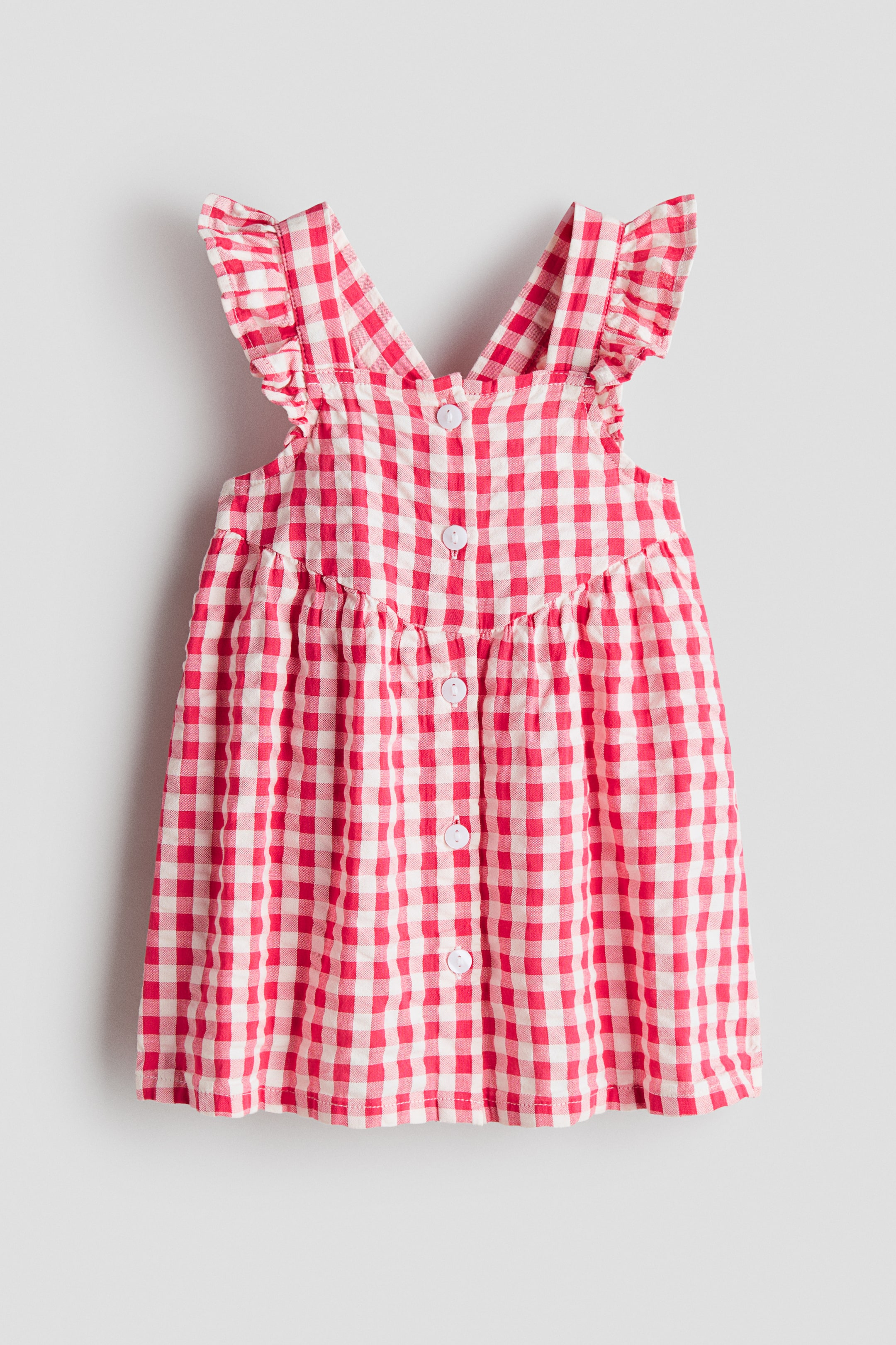 Se større billede: En knælang, ærmeløs kjole i rød- og hvidternet gingham-bomuldsvæv, vist forfra (FRONT), har skulderstropper med flæsekant og en firkantet udskæring. Hvide knapper løber ned foran, og en rynket søm markerer taljen.