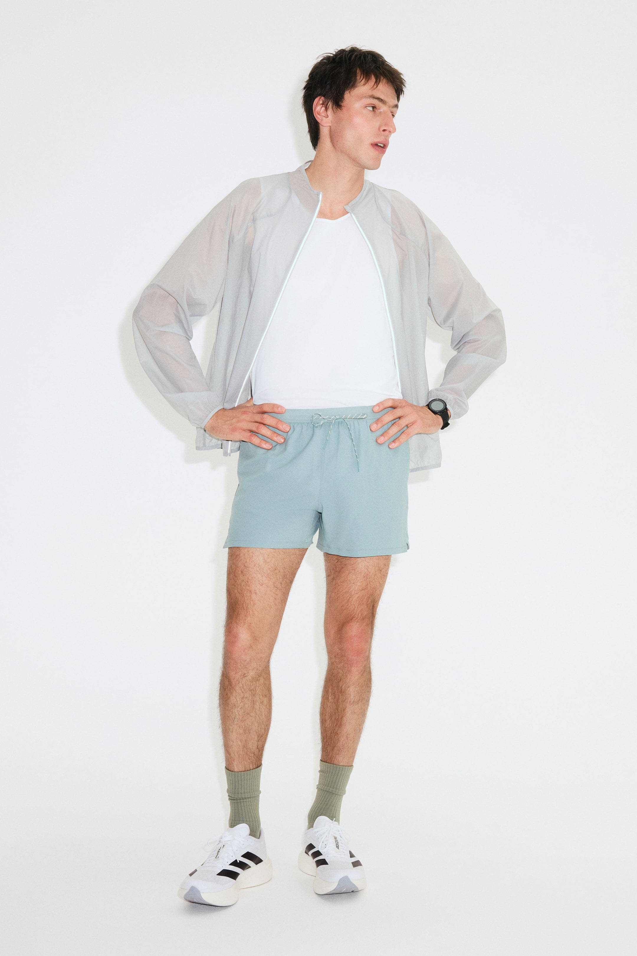 Agrandir l'image: Shorts de course légers à séchage rapide de couleur bleu sarcelle pâle portés par le mannequin. Les shorts présentent une taille élastiquée avec un cordon de serrage visible et sont stylisés sur un t-shirt blanc.