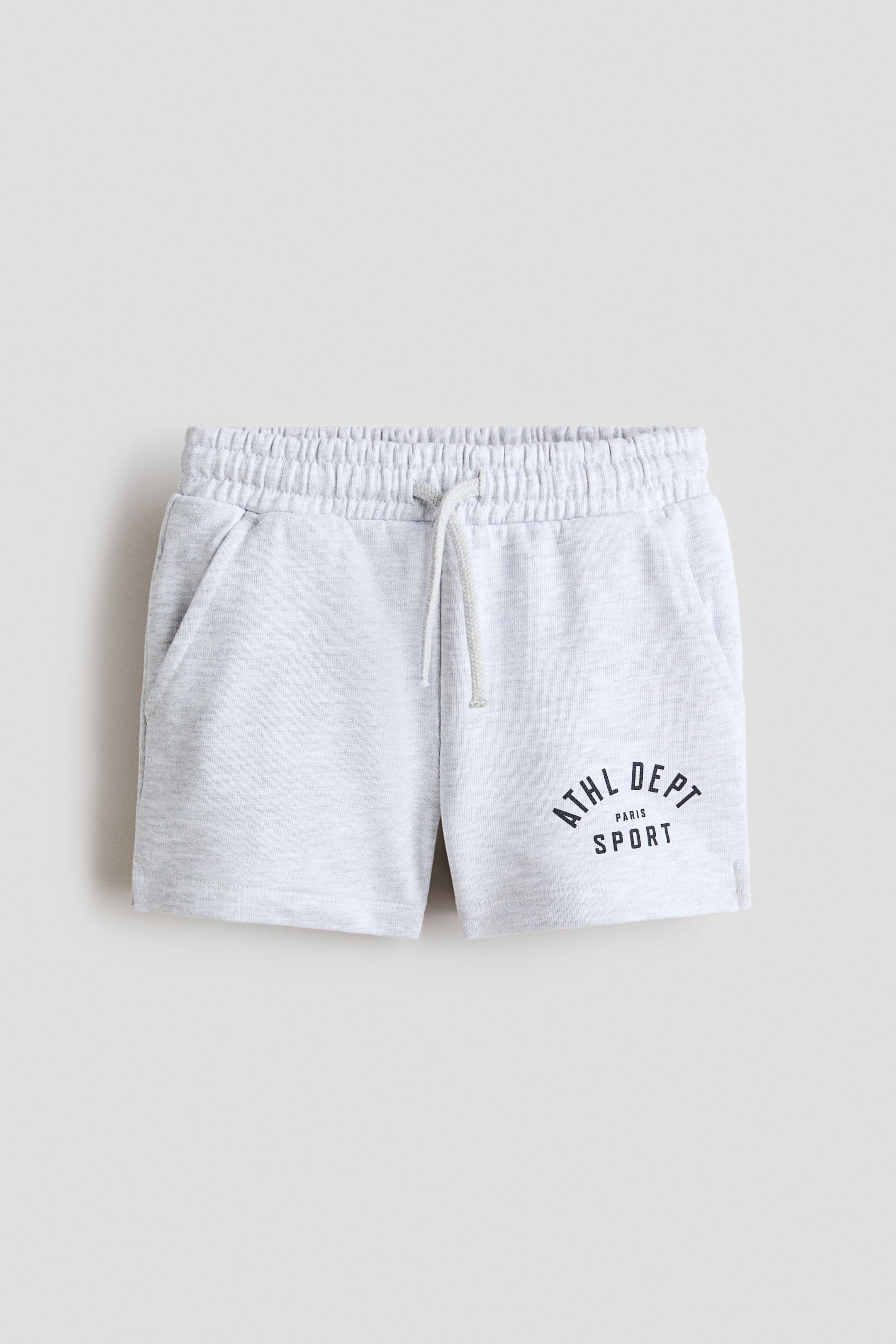 View larger image: Light grey marl shorts showcase an elasticated waistband with a white drawstring at the front, along with two angled pockets. A dark "ATHL DEPT PARIS SPORT" graphic adorns the lower right leg.