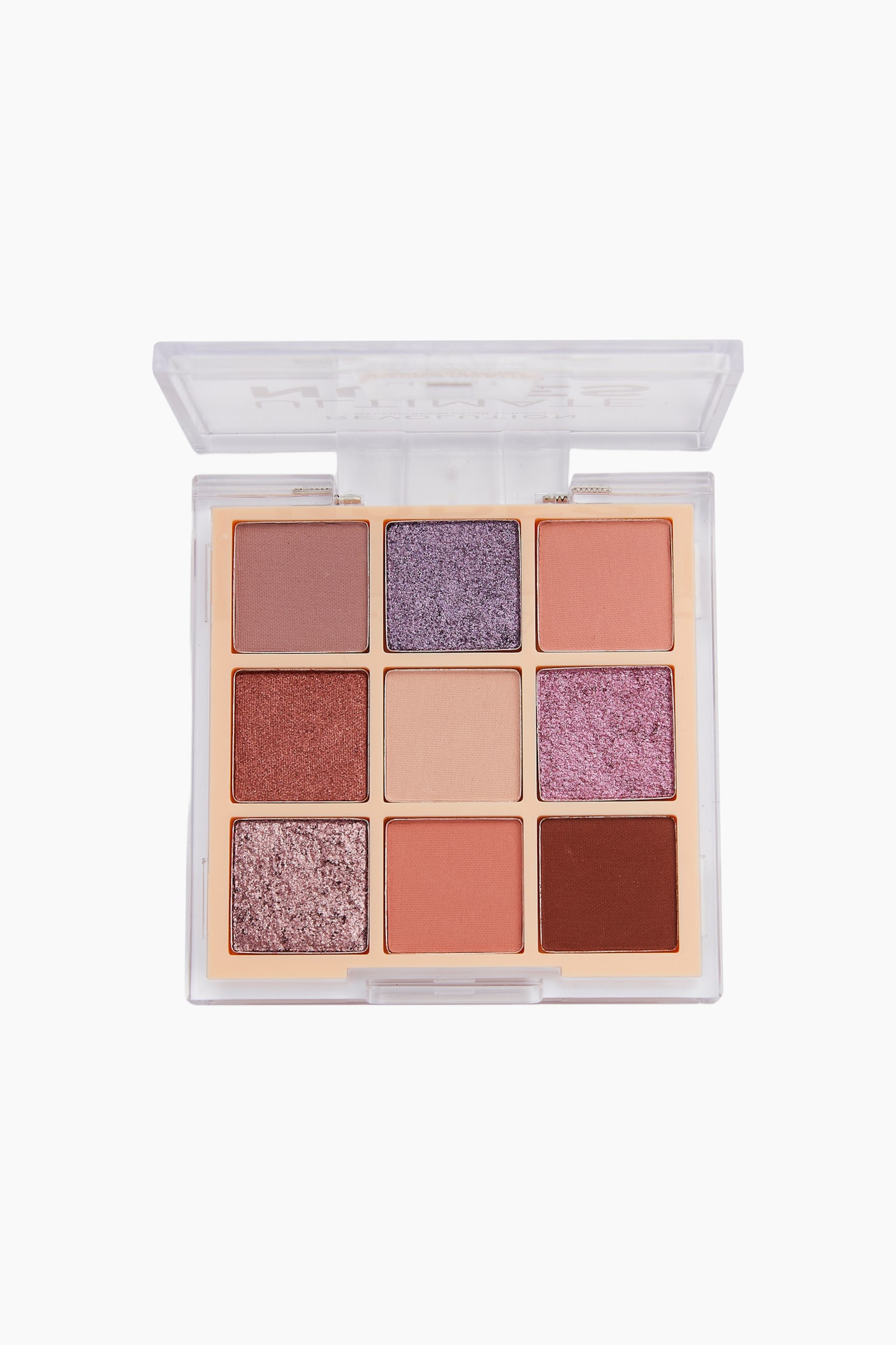 Die Revolution Ultimate Nude Shadow Palette ist in einer geraden, von oben aufgenommenen Ansicht zu sehen, wobei der transparente Kunststoffdeckel aufgeklappt ist und neun quadratische LidschattenpfÃ¤nnchen in einem Drei-mal-Drei-Raster zeigt. Die Kollektion prÃ¤sentiert eine Mischung aus fÃ¼nf matten FarbtÃ¶nen in Pfirsich, Beige, Mauve und Dunkelbraun sowie vier schimmernden und glitzernden Nuancen in Violett-, Kupfer- und RosatÃ¶nen.