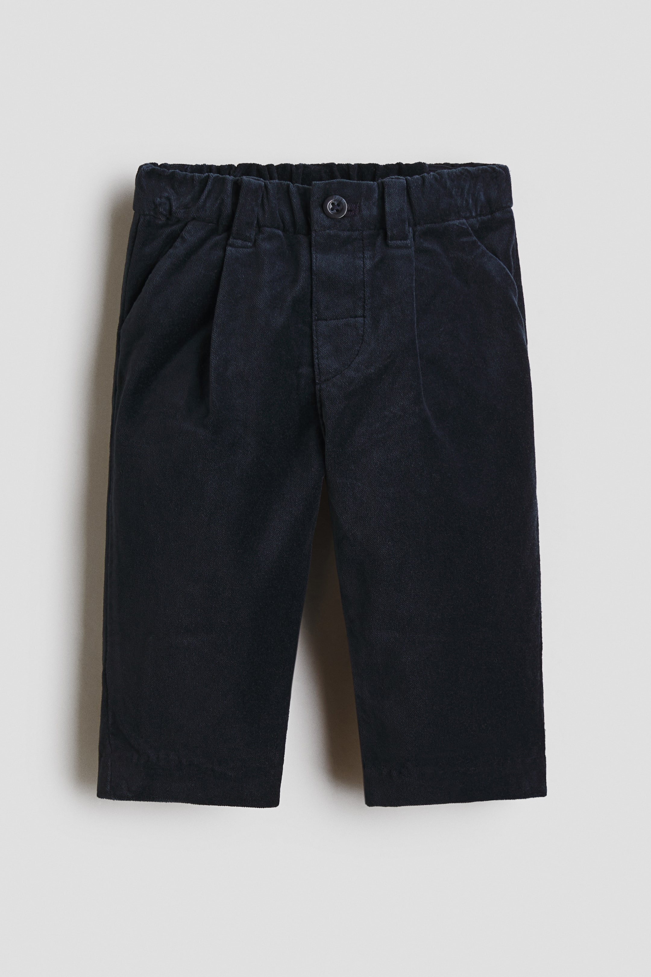 View larger image: Dark blue corduroy pants featuring an elasticated waistband with belt loops, a single-button closure, two angled side pockets, and two front pleats.