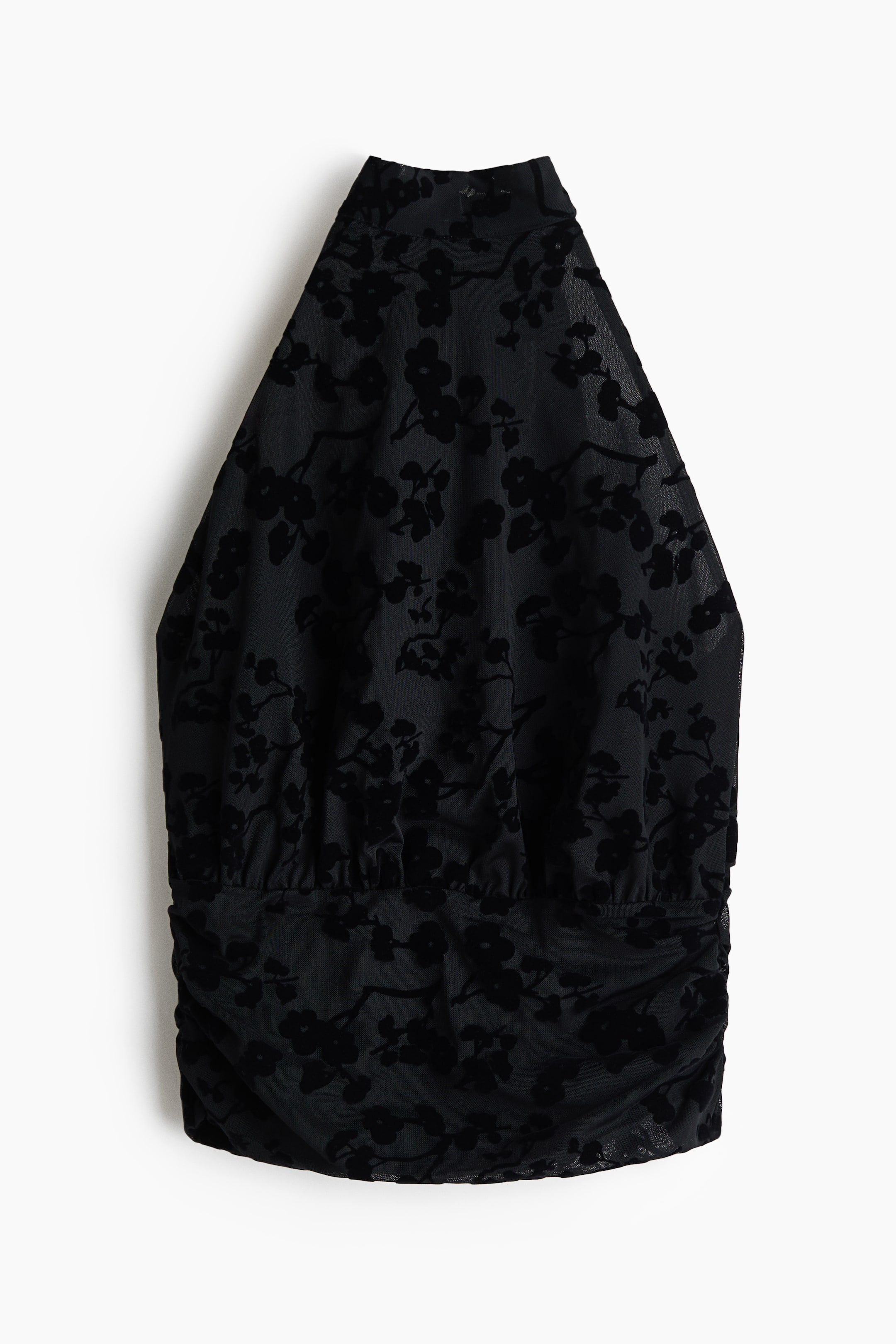 Größeres Bild anzeigen: Ein schwarzes Neckholder-Top mit beflocktem Blumenmuster auf transparentem Mesh-Gewebe. Der untere Teil des Tops ist mit Raffung gestaltet, wodurch ein geraffter Effekt am Saum entsteht.