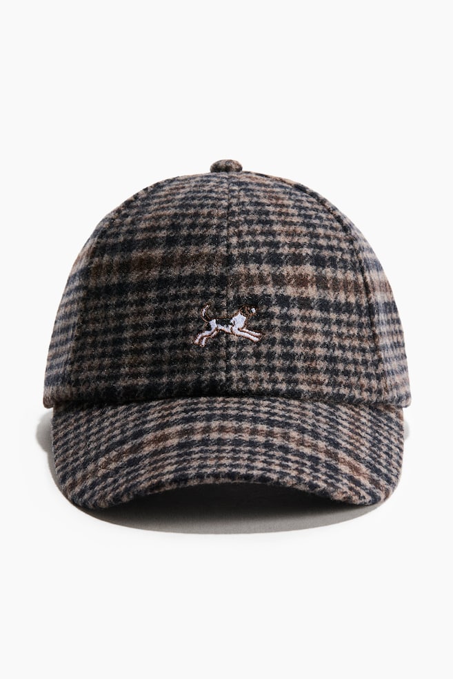 A front-facing view of a wool-blend baseball cap featuring a brown, black and grey patterned plaid with a soft, textured finish. The cap is displaying a small embroidered running dog on the centre front of the crown. - 1