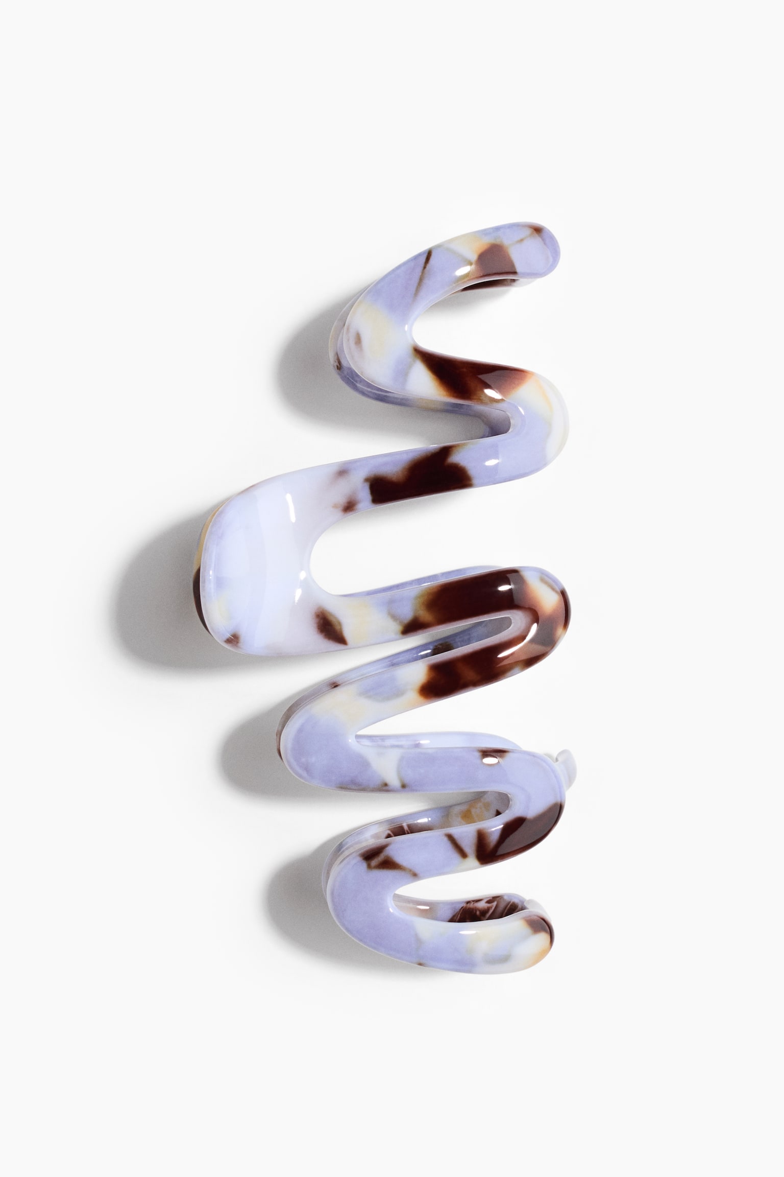 A hair claw clip in glossy plastic is on display, featuring a vertical, wavy design. The clip has a marbled pattern in shades of lavender, cream, and dark brown. - 1