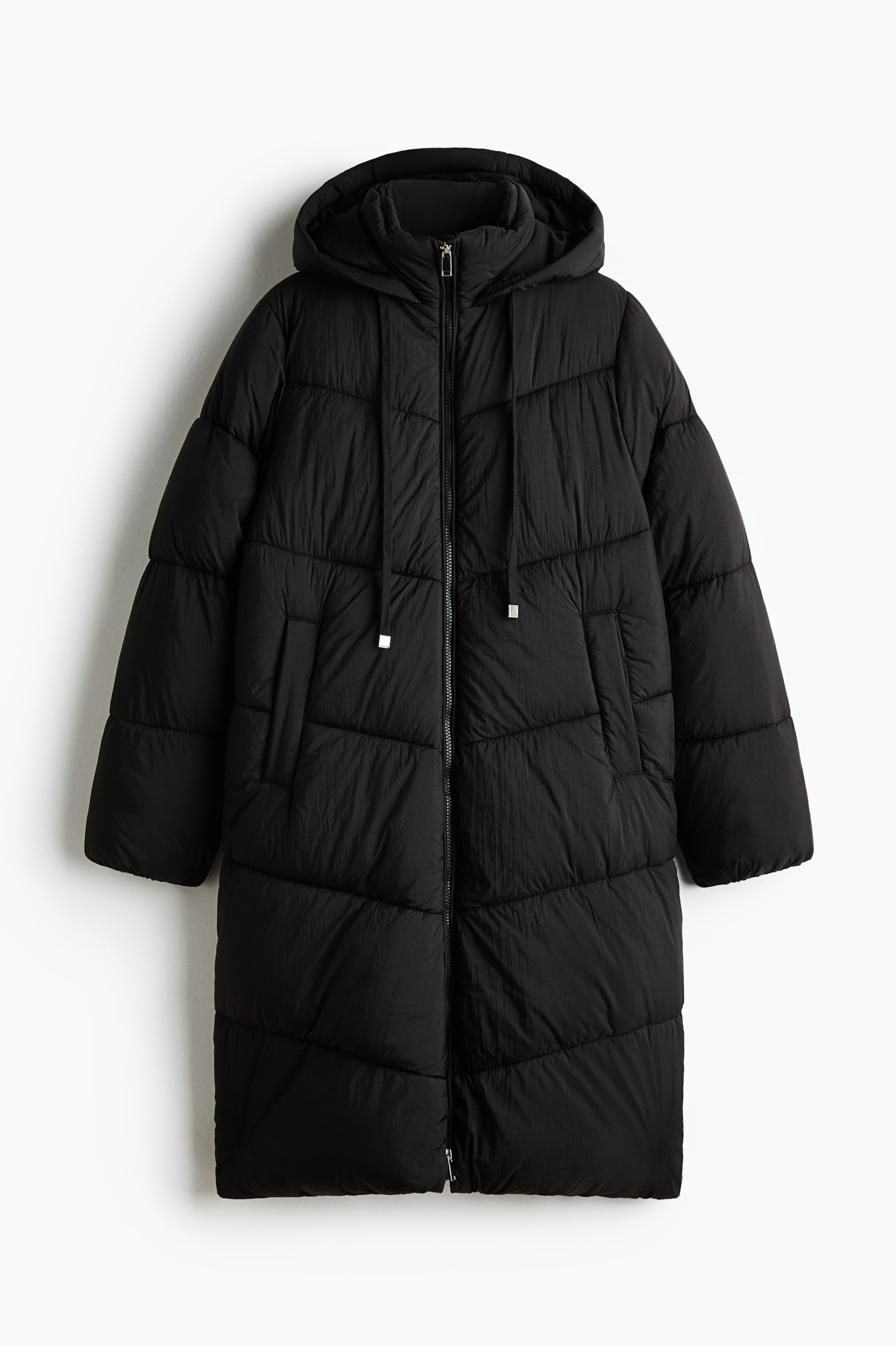 View larger image: A long black puffer coat is shown from the front, featuring horizontal quilting and a full-length front zip. The coat has an attached hood with adjustable drawstrings and two side welt pockets.