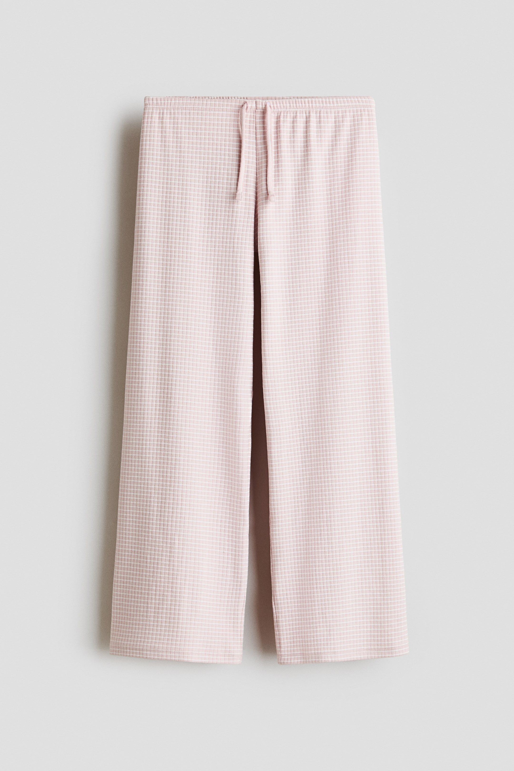 Ver imagen más grande: Los pantalones se presentan en vista frontal, con un estampado de microcuadrícula en rosa claro y blanco y un corte de pierna ancha con cintura elástica ajustable con cordón.