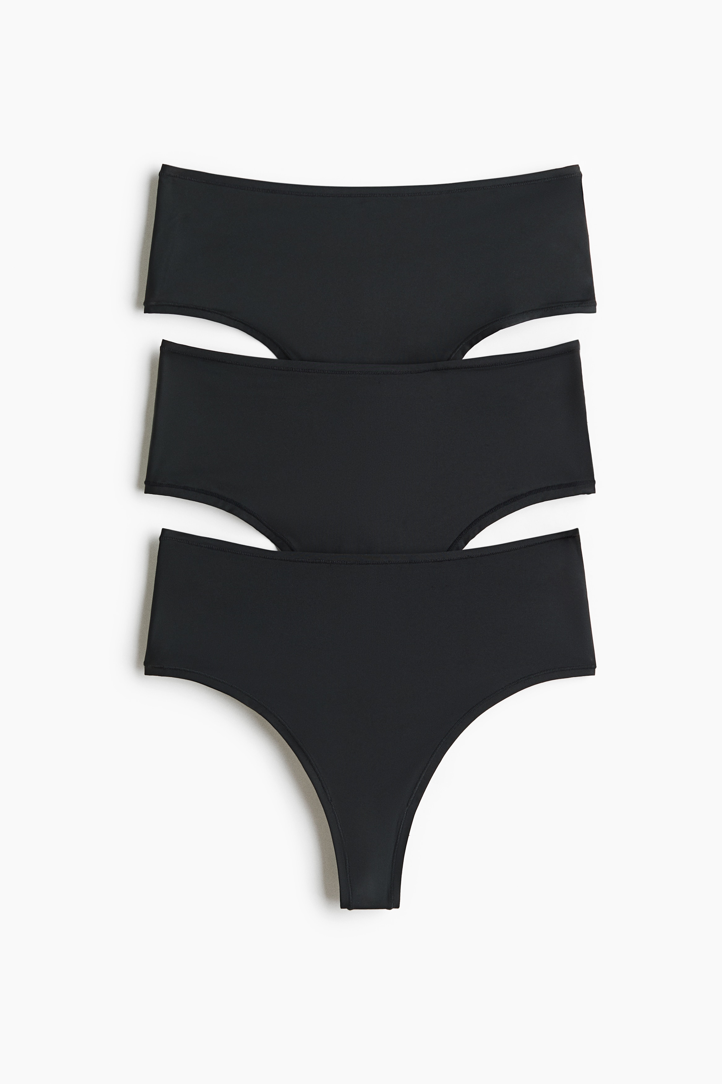 A black bra with thin straps and matching high-cut briefs are being presented from a front-facing angle. An open white shirt is loosely draped over the shoulders and arms, partially revealing the underwear set.