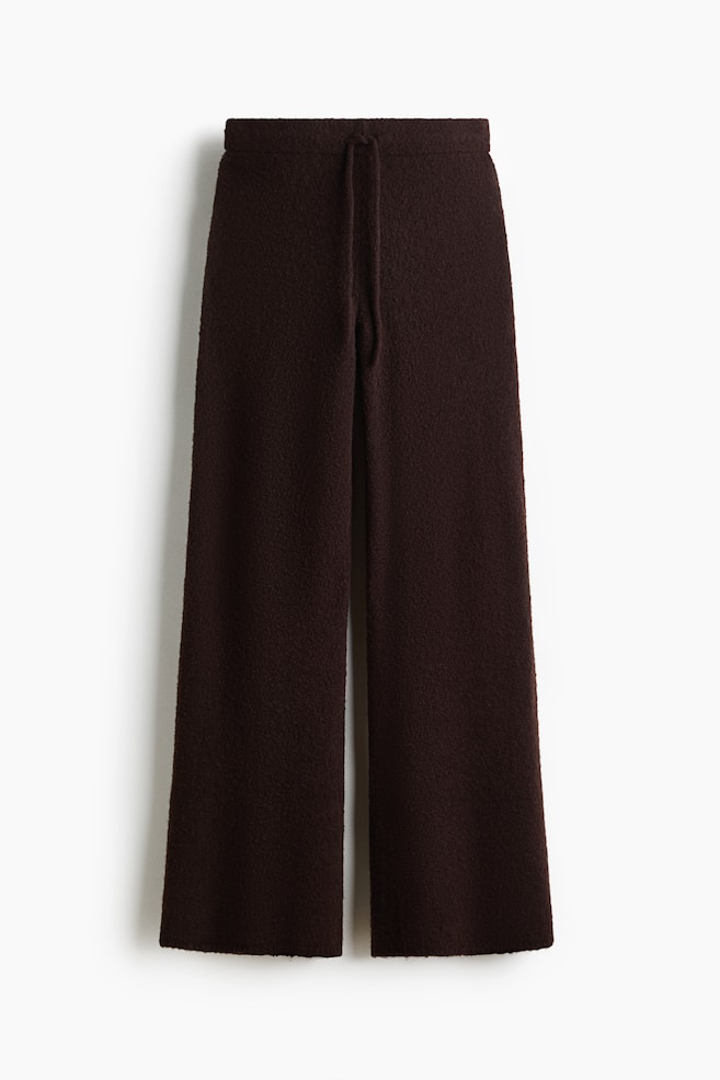 A pair of dark brown, textured knit pants is facing forward, featuring a relaxed, wide-leg silhouette. The pants are showcasing an elasticated waistband with a matching drawstring hanging at the center. - 1