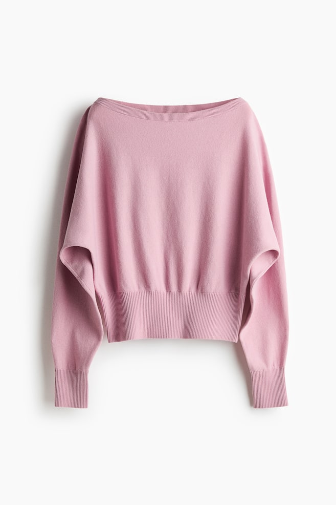 Un jersey rosa muestra su forma holgada y drapeada desde un ángulo frontal, con un escote barco. Destaca por sus mangas dolman anchas, un dobladillo acanalado y puños acanalados. - 1