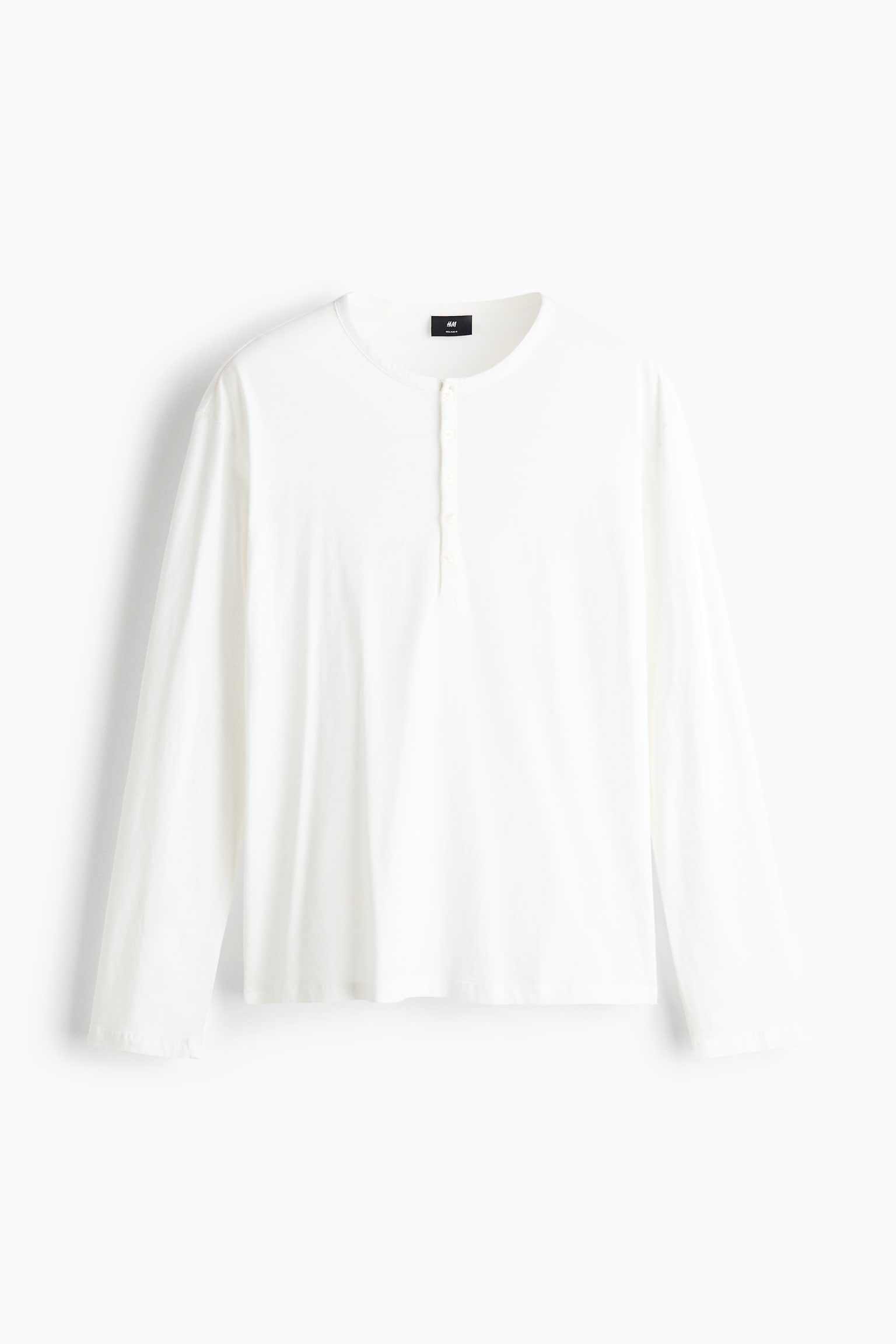 A long-sleeved, off-white Henley shirt is shown front on, featuring a round neckline with a buttoned placket. The shirt has a relaxed fit with straight-cut sleeves and a simple, clean hemline.