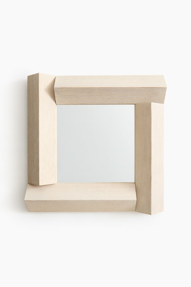 Een spiegel met een rechthoekig ontwerp en een lichtgekleurde houten lijst, met zichtbare houtnerf en gelaagde constructie. De horizontale delen van de lijst zijn breder dan de verticale delen, met schuine randen die geometrische, overlappende hoeken vormen. - 1