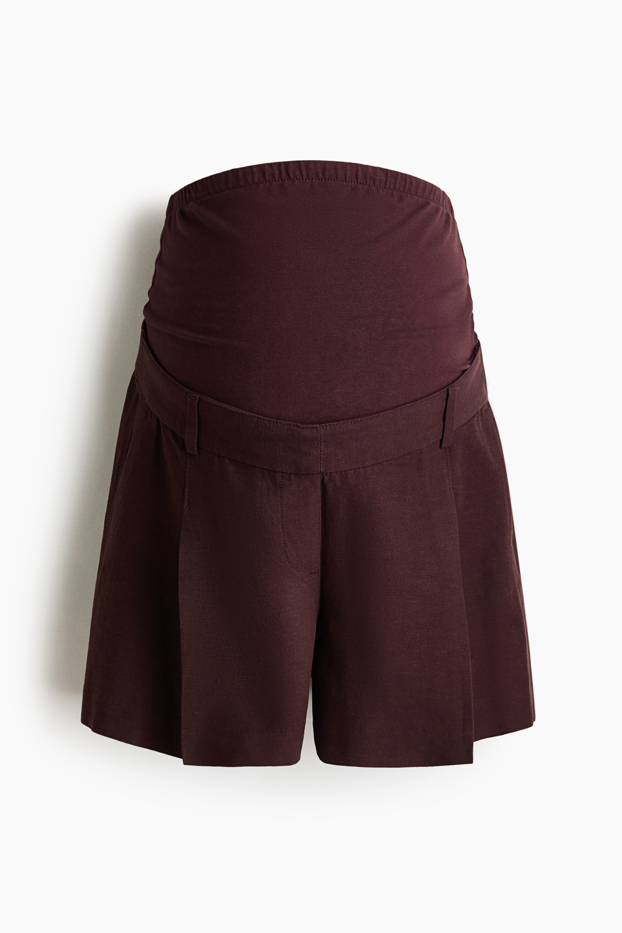 View larger image: Dark brown tailored shorts are featured from the front, highlighting an airy weave, a wide jersey panel forming the upper waist, pleats and creases detailing the front, and diagonal side pockets.