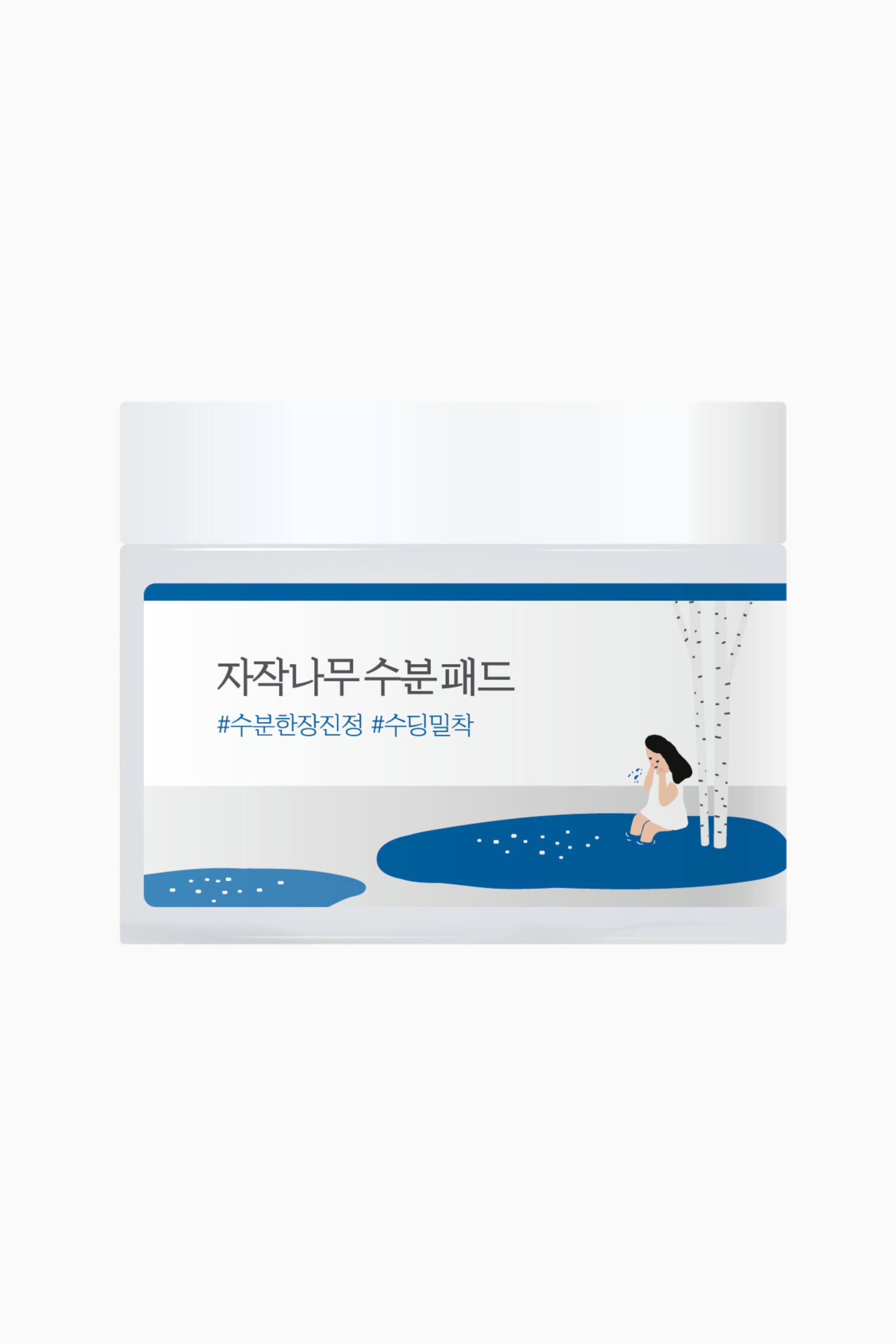 Vis større bilde: En hvit, rektangulær produktbeholder viser fronten og har en etikett med koreansk tekst. Etiketten viser også en illustrasjon av en person som sitter i et blått vannbasseng, flankert av stiliserte bjørketrær og blå vannformer.