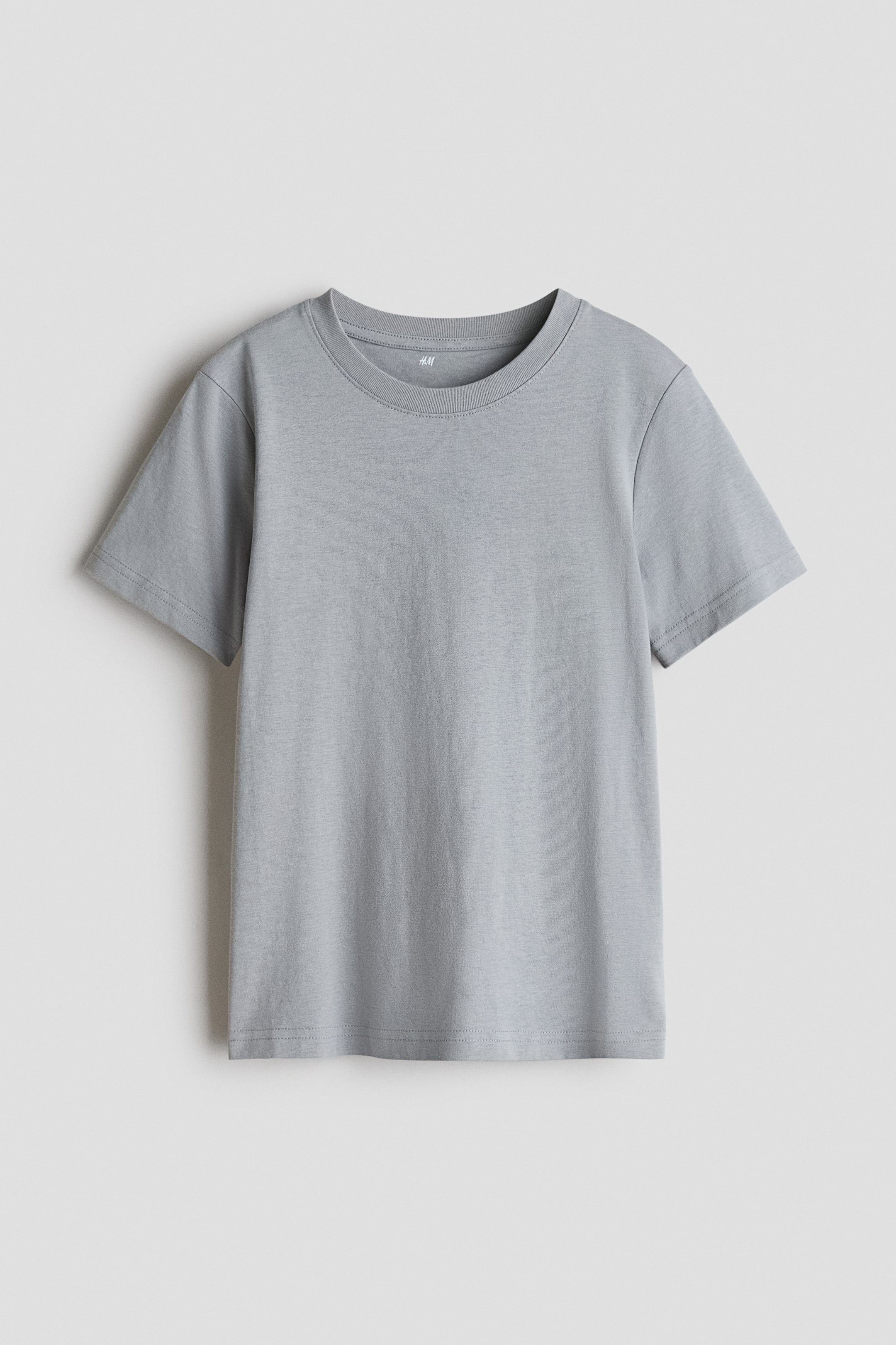 Voir une image plus grande: Un t-shirt gris clair est orienté vers l'avant, avec un col rond, des manches courtes et un ourlet droit, arborant une étiquette H&M visible à l'intérieur du col.