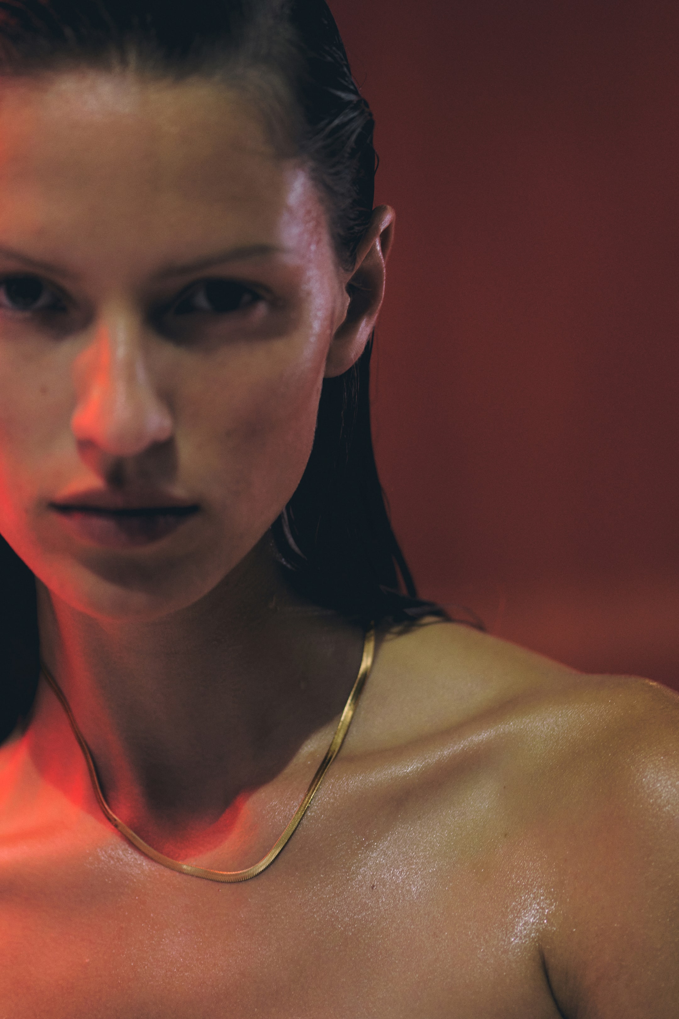 이미지 확대 보기: 골드 톤의 스네이크 체인 목걸이가 착용자의 쇄골에 직접 닿아 있으며, 평평하고 반사되는 표면을 지닙니다.